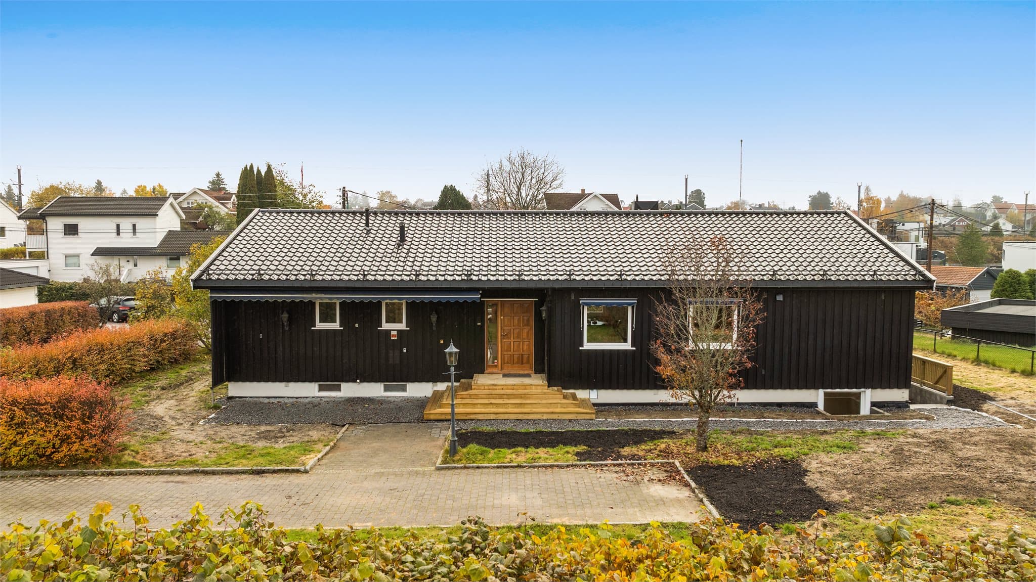 Flatt og lettstelt inngangsparti med belegningsstein foran huset.
