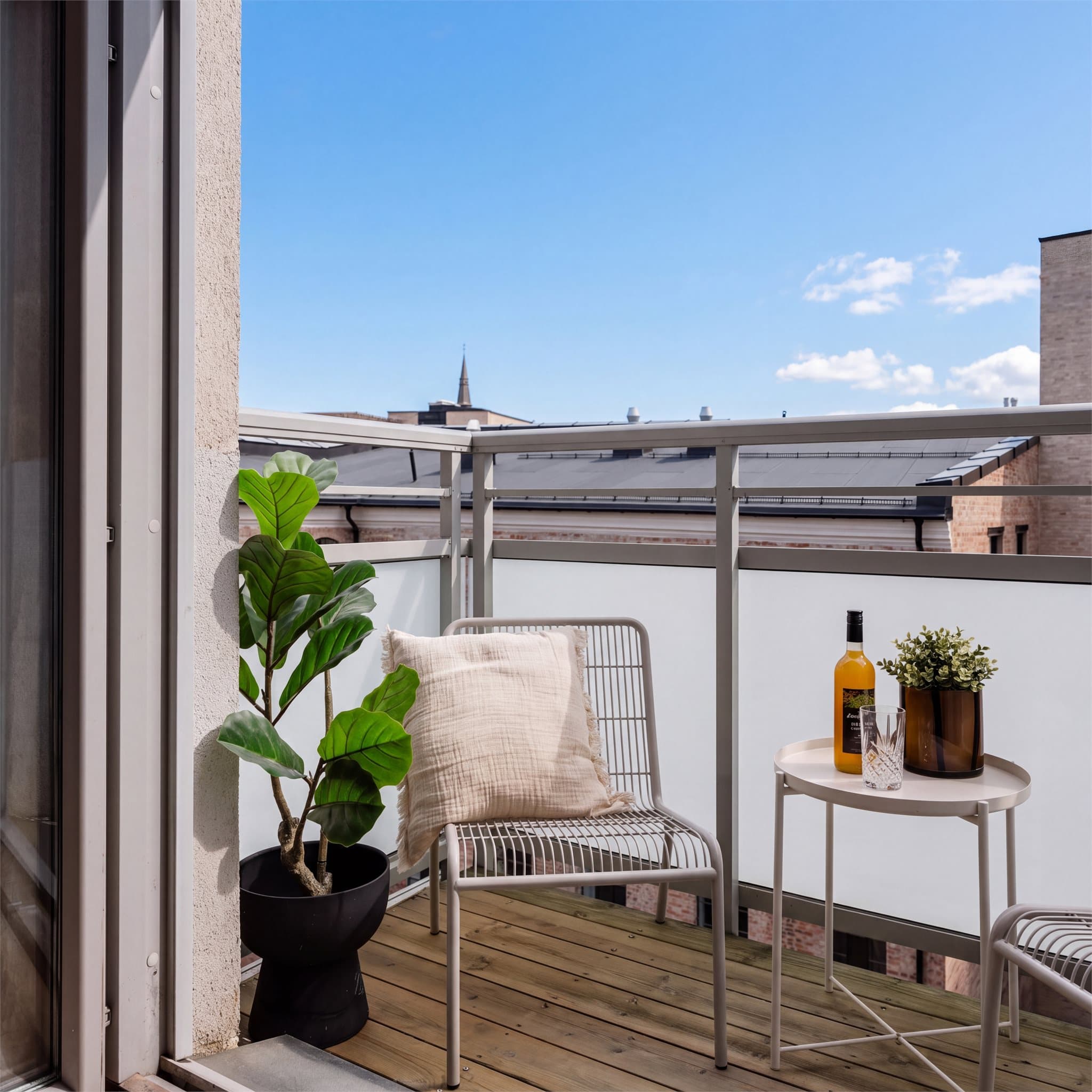 Balkongen har dekke av terrassebord og rekkverk i aluminium med herdet, frostet glass som skjermer for innsyn.