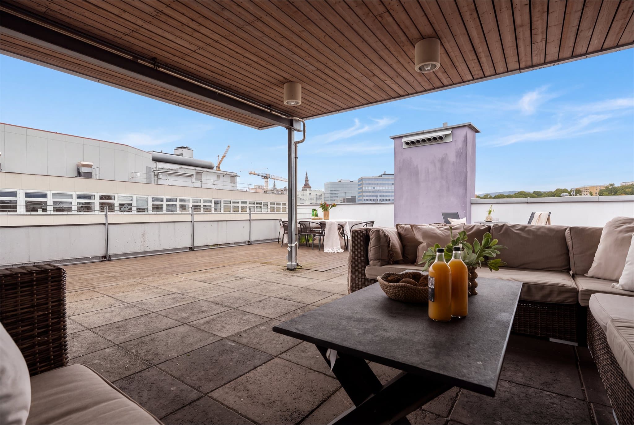 Takterrassen er dekket med steinheller og terrassebord under et overbygd parti.