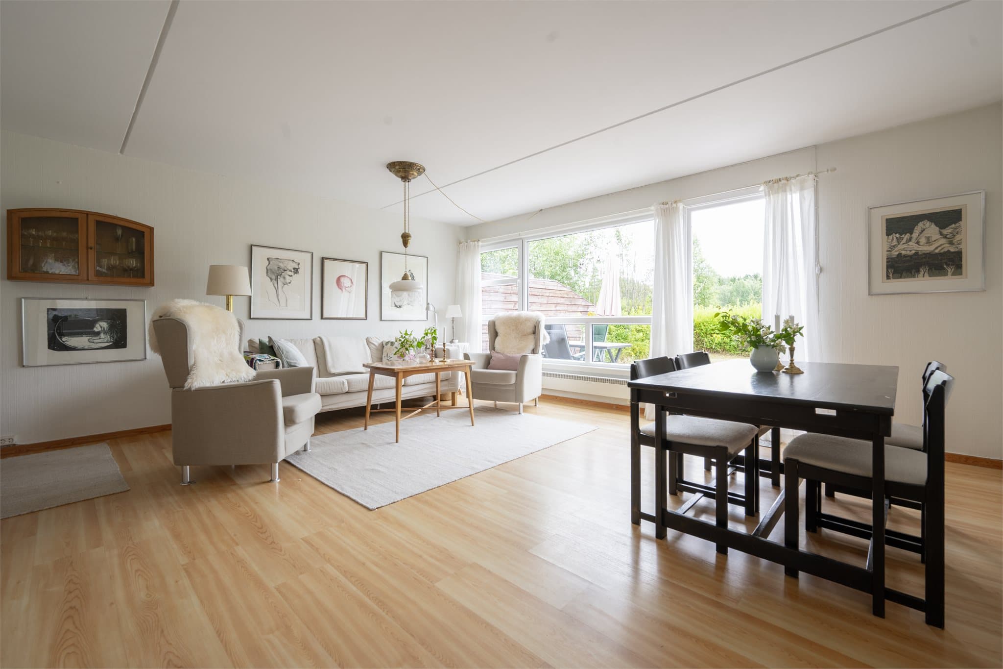 Med utsyn til hagen og lyset som strømmer inn gjennom de store vinduene, får stuen en varm og harmonisk atmosfære som er lett å trives i.