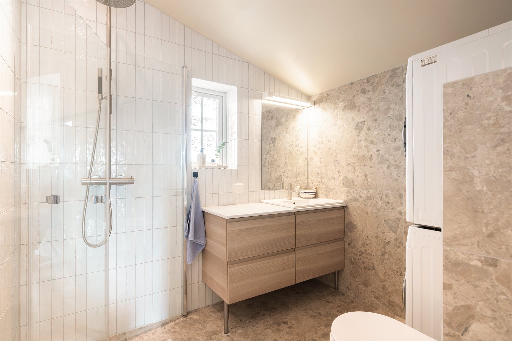 Badet i andre etasje er lysere og lunere, med en moderne dusjone med takdusj og glassvegger som tilfører både eleganse og funksjonalitet.