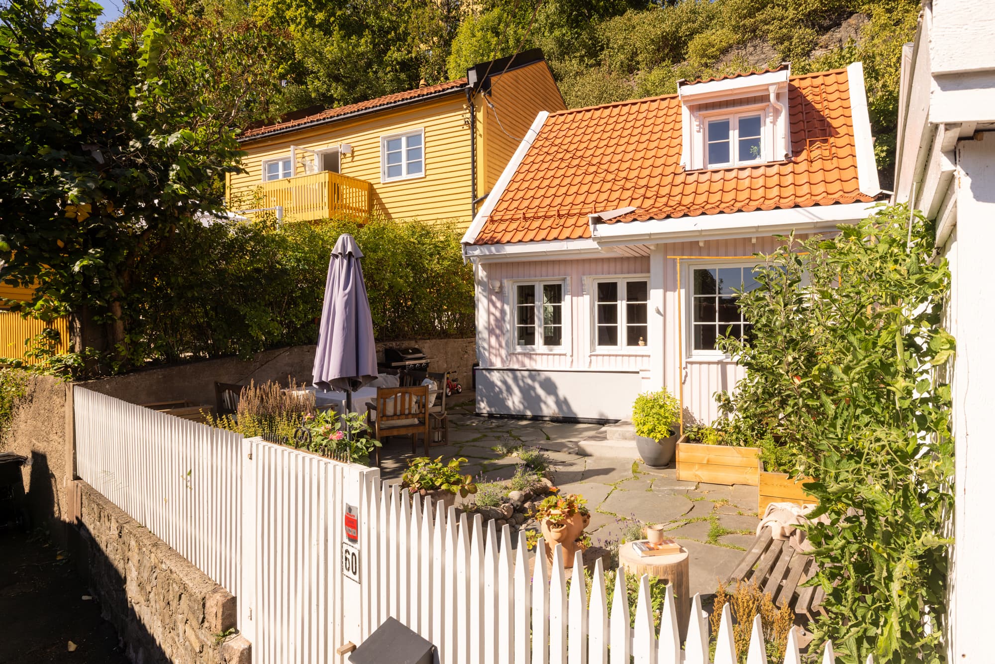En sjarmerende port i det klassiske, hvite gjerdet og en flott steintrapp leder opp til boligen.