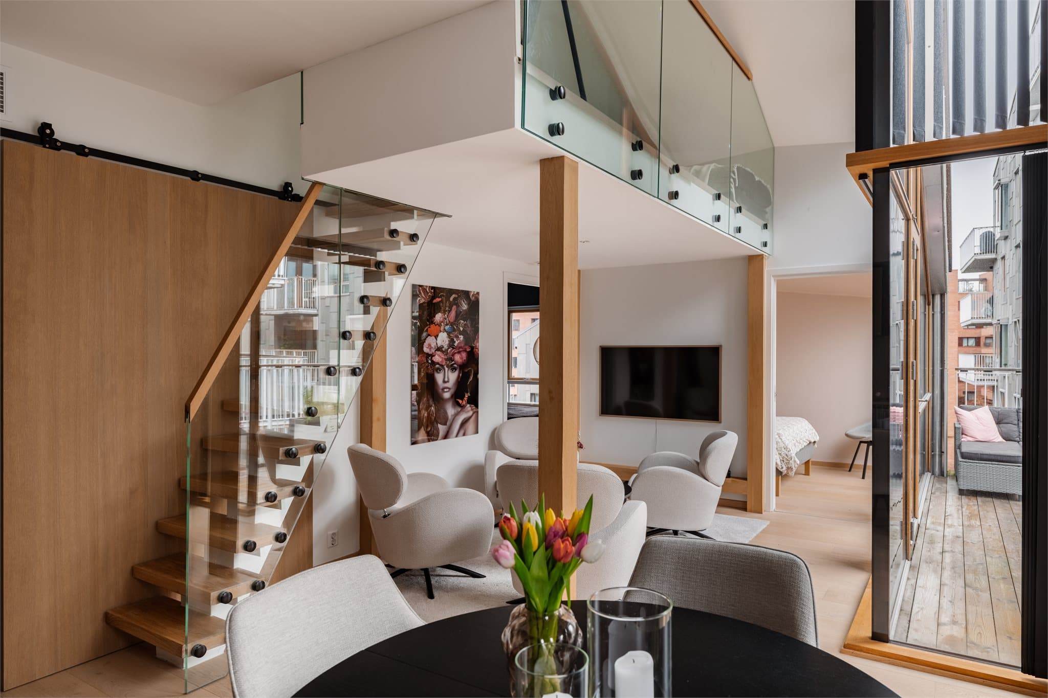 Oppholdsrommet fremstår som særdeles lyst og luftig, med imponerende takhøyde og store vindusflater som slipper inn rikelig med naturlig lys.