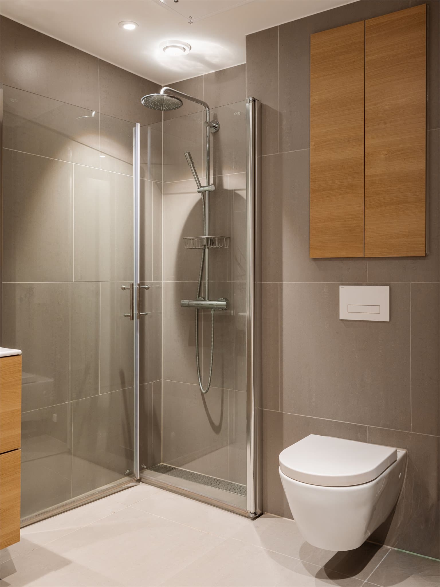 Romslig dusjplass på gulv bak dører i herdet glass.