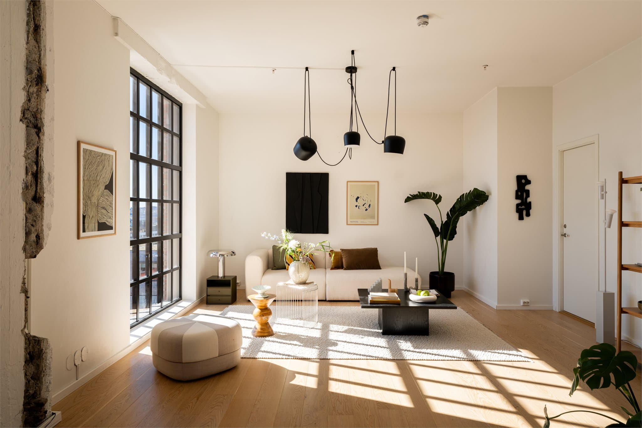 Leiligheten er nøye planlagt for å skape funksjonelle og harmoniske oppholdsrom, med et gjennomgående moderne uttrykk som balanserer varme materialer og sorte, stilrene detaljer.