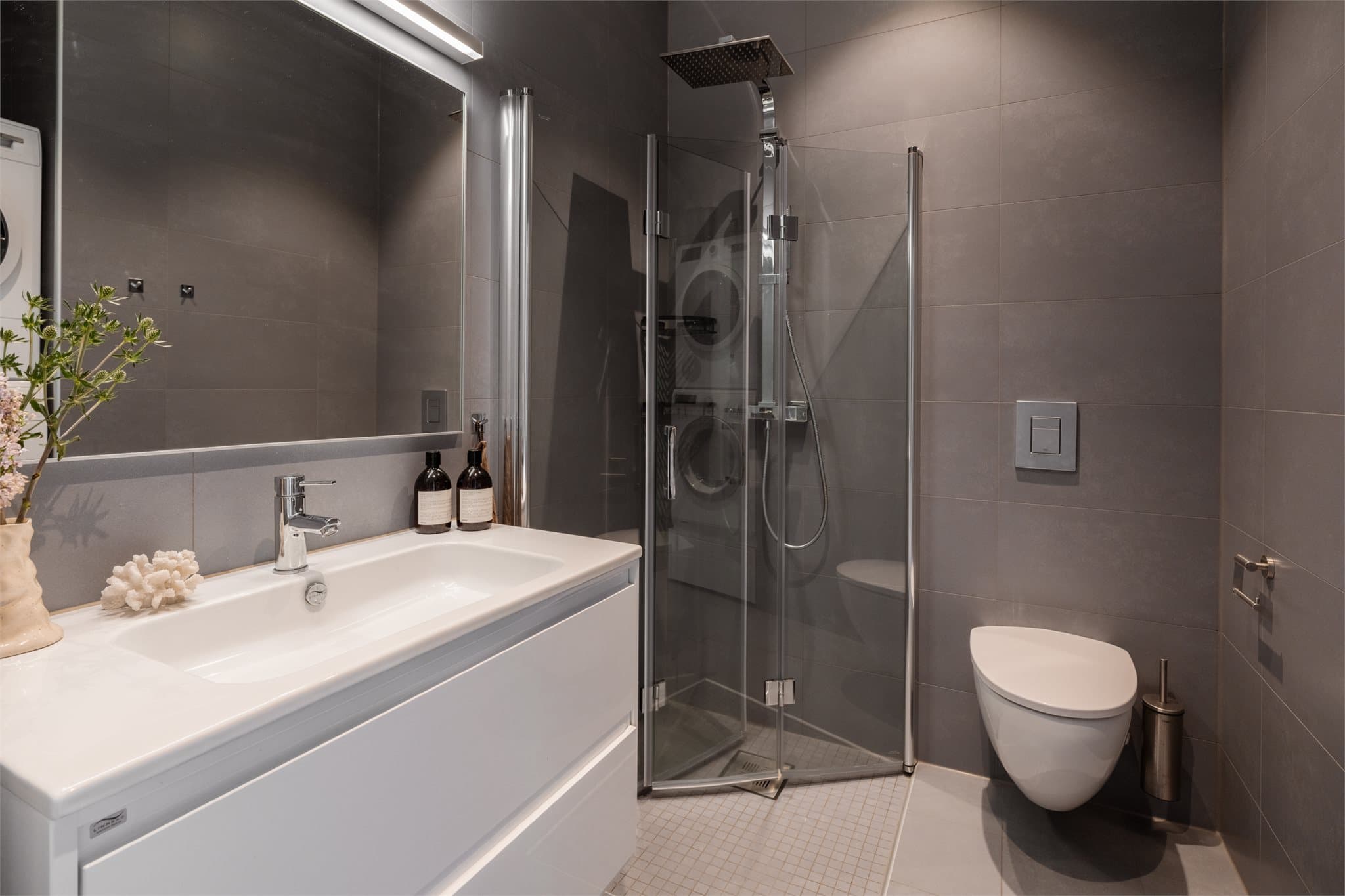 Rommet er helfliset med fliser på både gulv og vegger, noe som gir et gjennomført og elegant uttrykk.