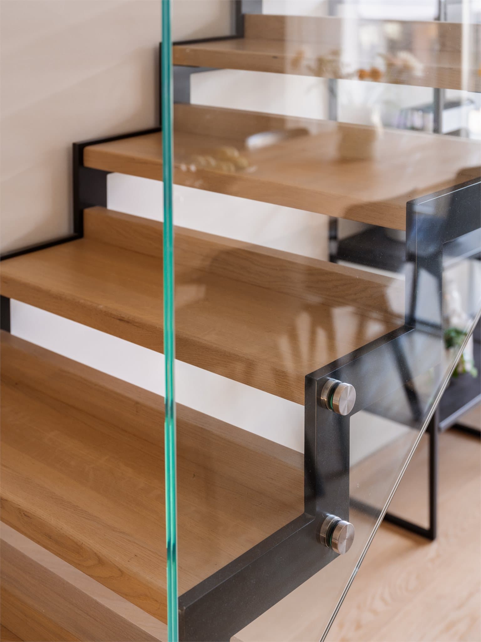 Trappen har lakkerte stålvanger, trinn i hvitpigmentert heltre eik og rekkverk i herdet glass.