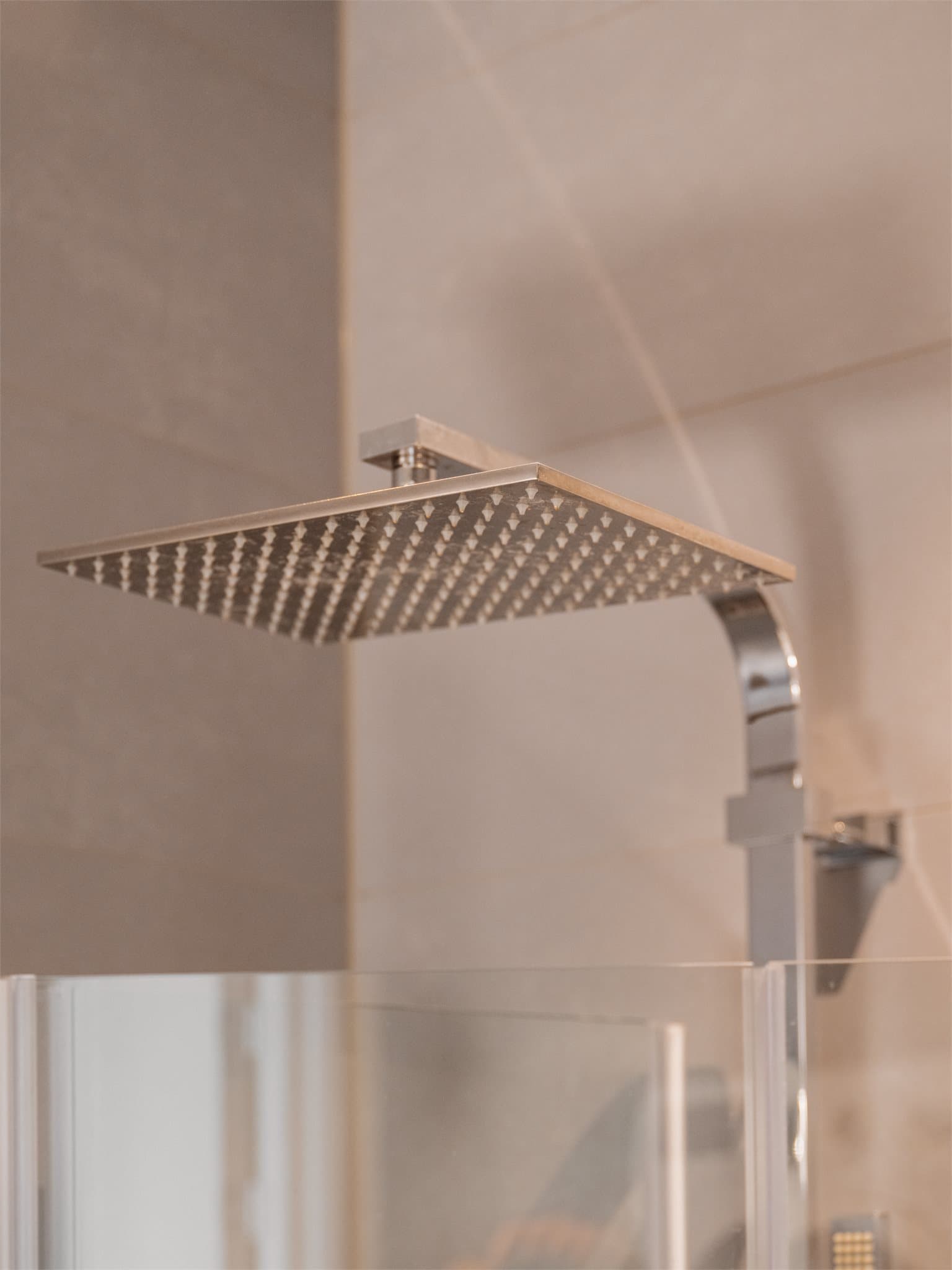 Dusjen har dusjdører i herdet glass og er montert direkte på gulvet, noe som gir et åpent og romslig inntrykk.