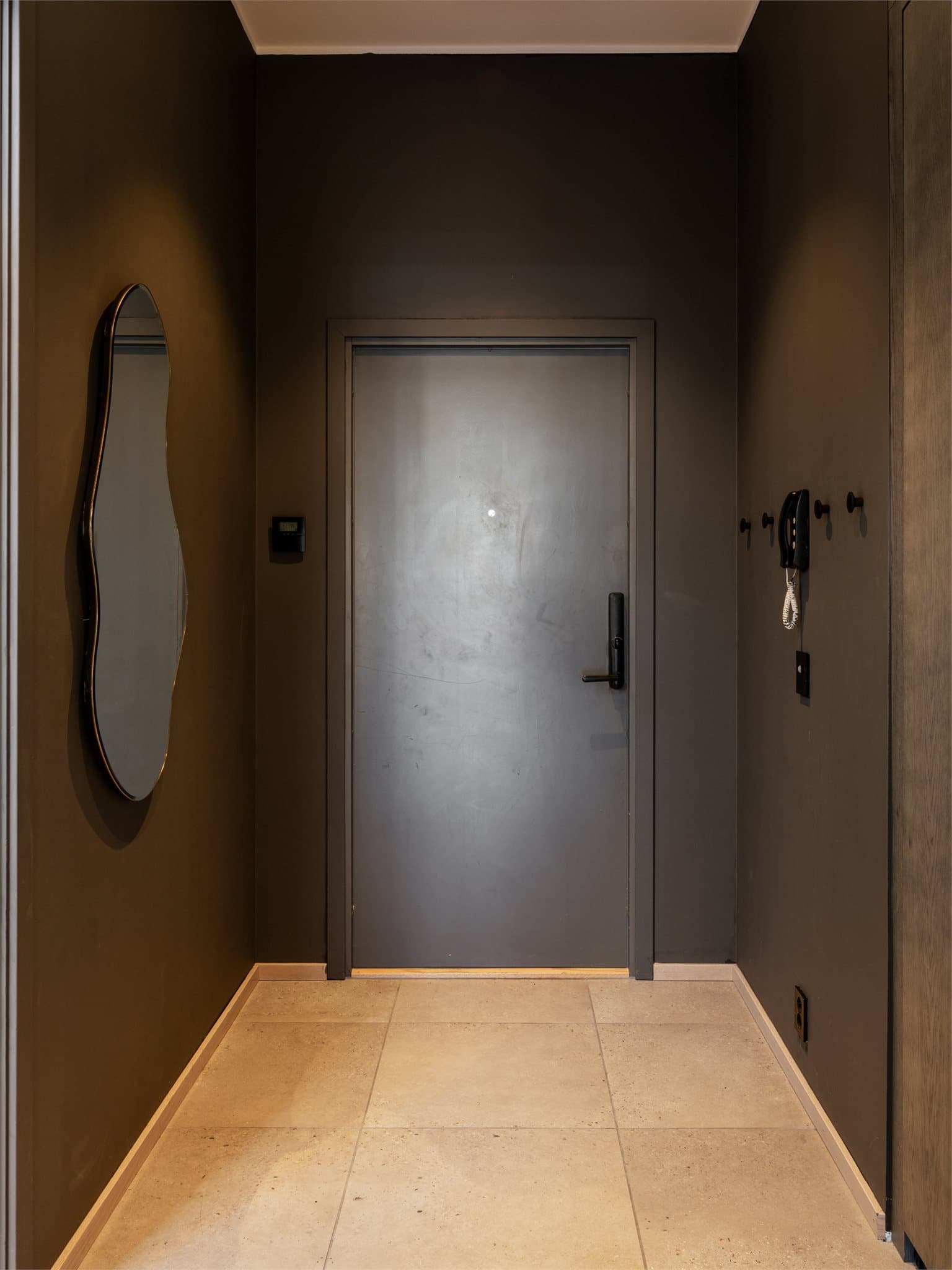 Leiligheten har en romslig og innbydende entré med flislagt gulv i en tidløs, grå nyanse som gir et moderne og rent uttrykk.