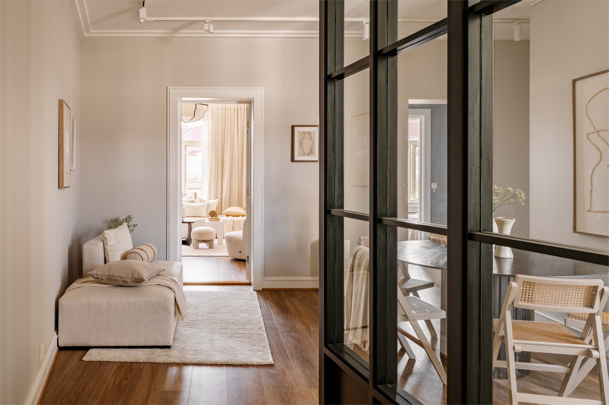 Lys leilighet med behagelige fargetoner, en mørk glassvegg og gjennomtenkte detaljer som skaper en elegant og lun atmosfære.