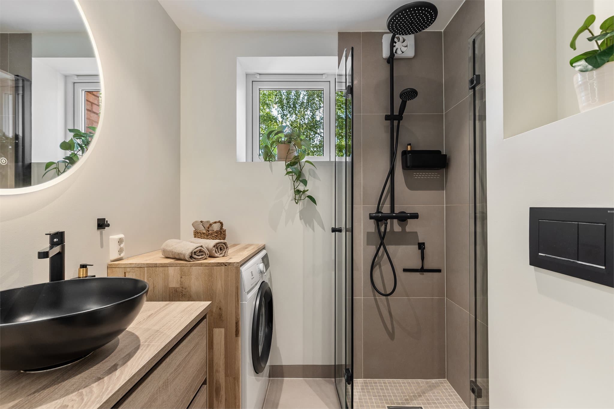 Det er varme i gulvflisene samt en praktisk nisje av tre med plass til vaskemaskinen