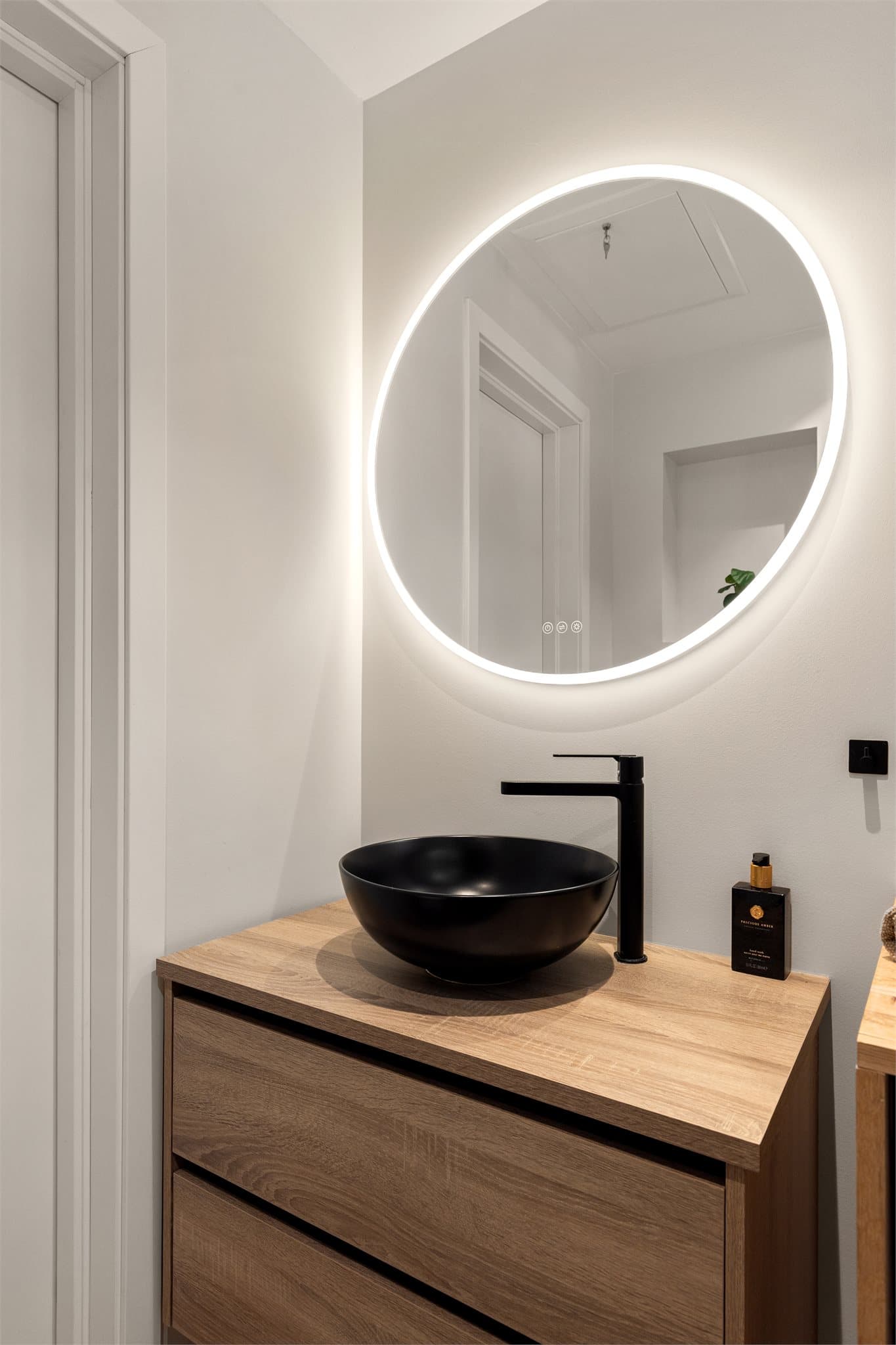 Speil med belysning samt stikkontakt på vegg over servant