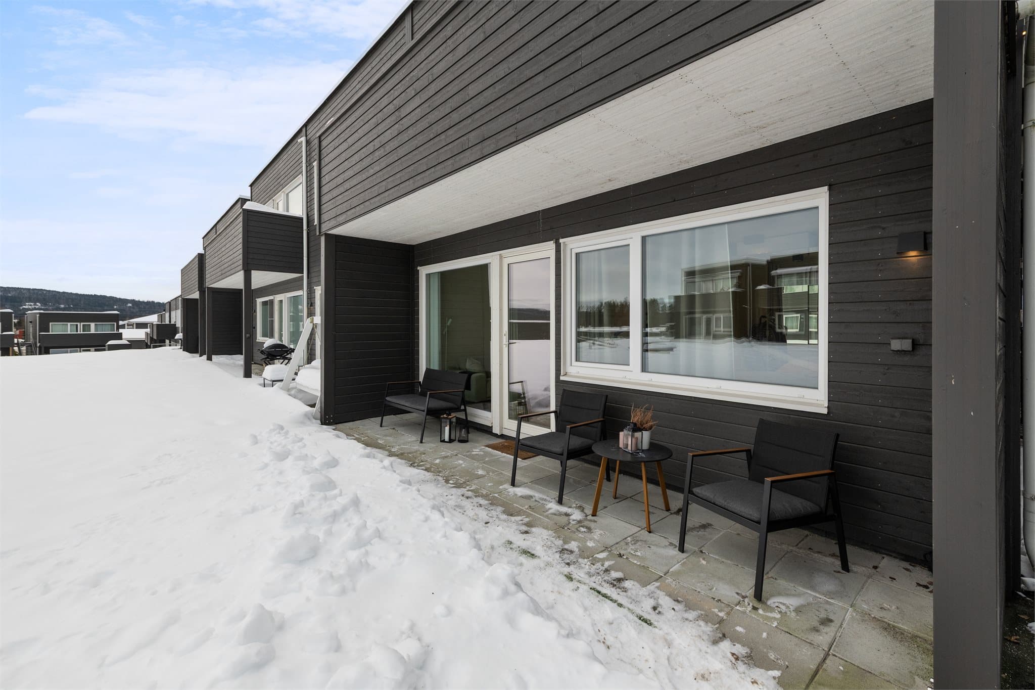 Hyggelig skjermet, hellelagt terrasse med fellesområde og plen i forkant