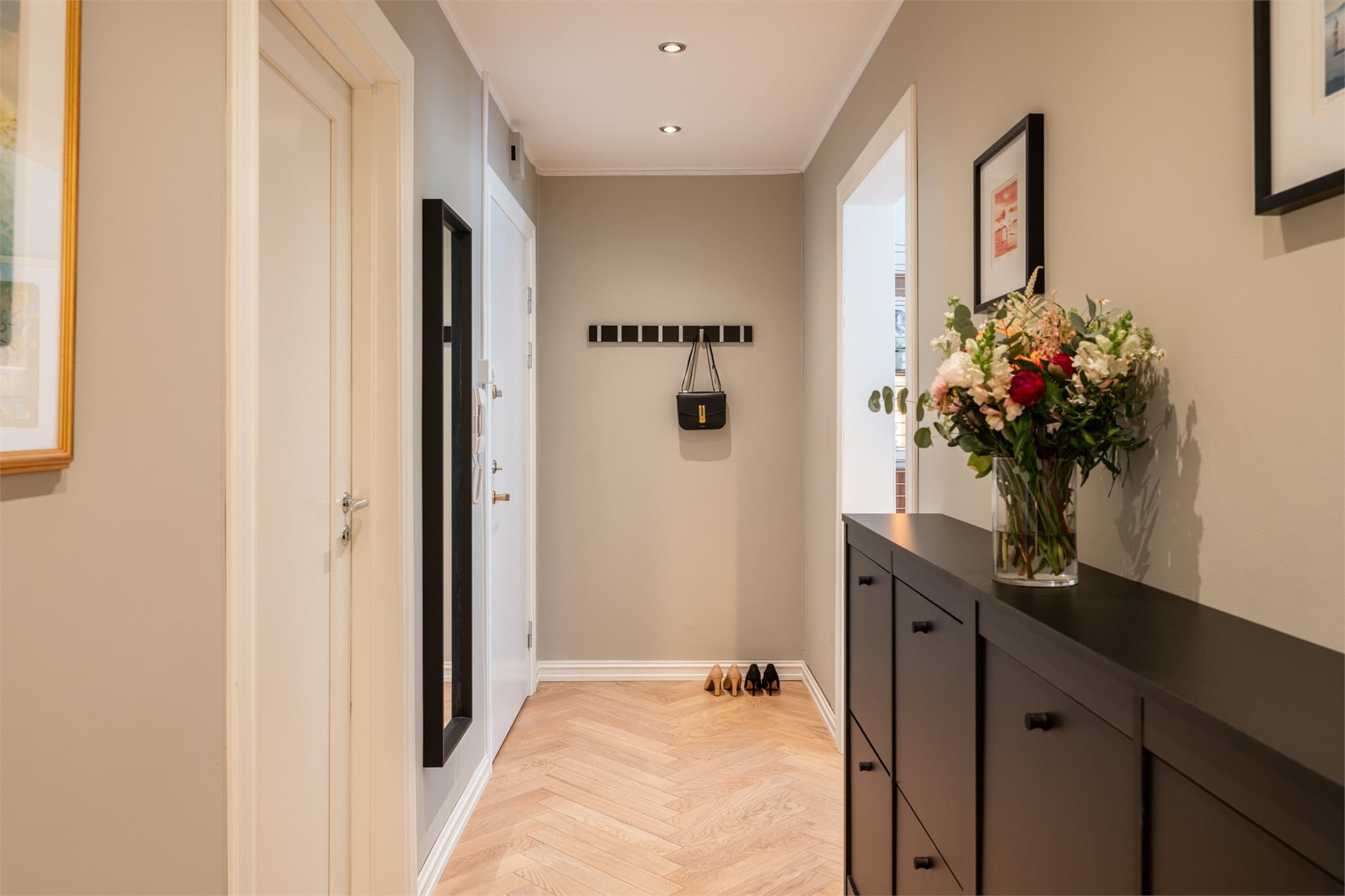 Romslig, innbydende entré med downlights i himlingen og fiskebensparkett.