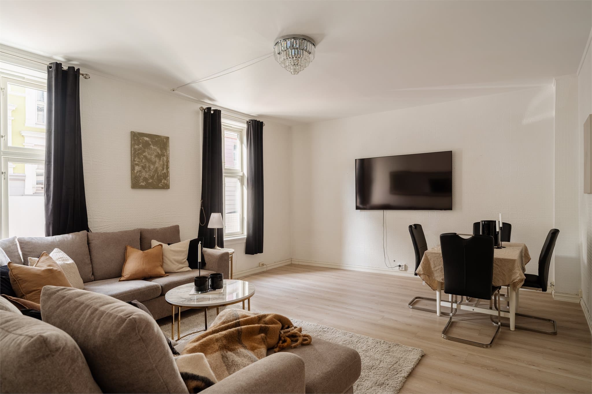 En romslig stue med plass til både sofagruppe, spisebord og TV-møbler.