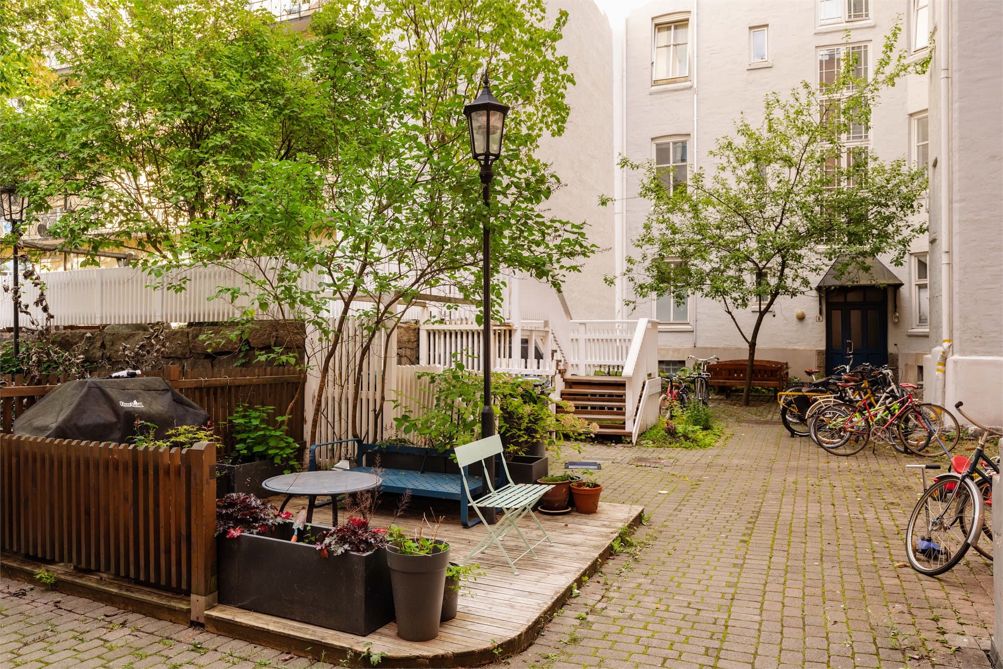Skjermet og hyggelig treplatting med sitteplasser og grillmuligheter, en grønn og lun oase for hyggelige sammenkomster.