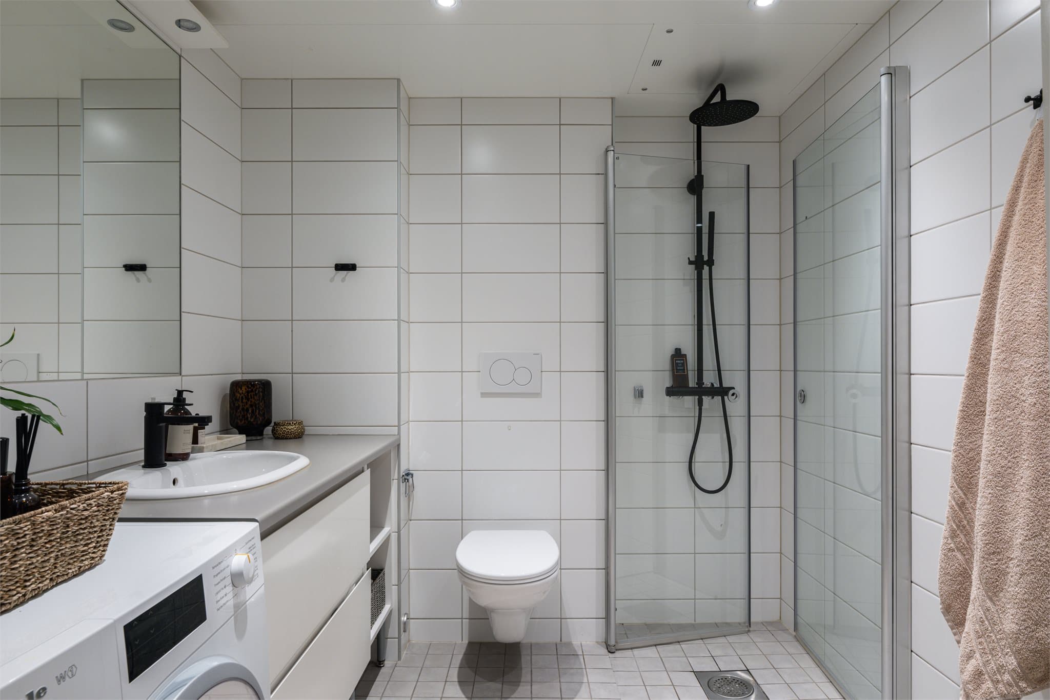 Badet byr på lyse fliser, innfelt belysning og moderne innredning.