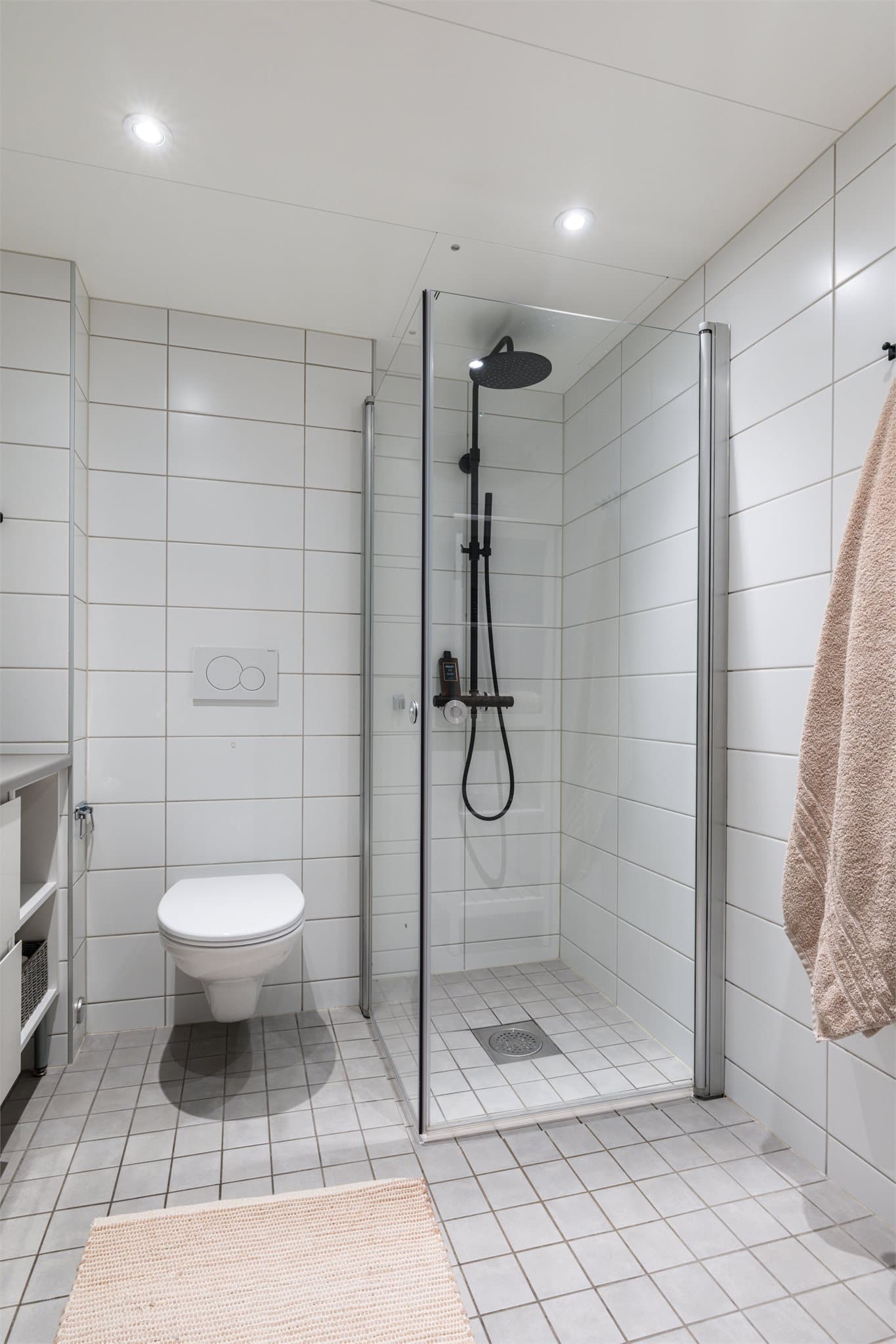 Romslig regnfallsdusj bak innfellbare dusjdører.