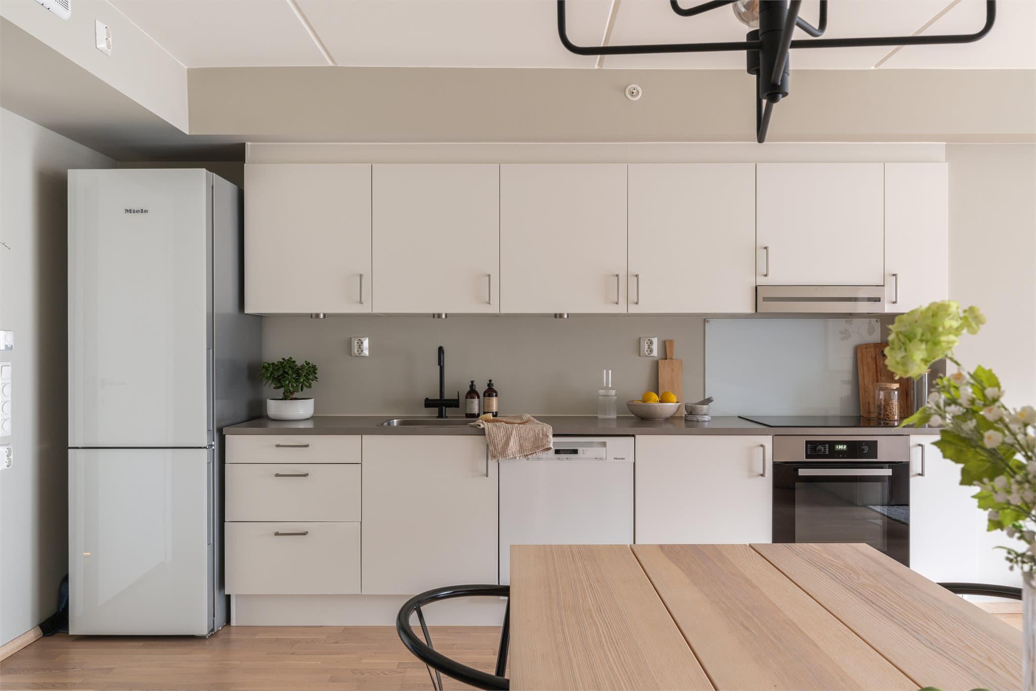 Lyst, tidløst kjøkken med hvitevarer som medfølger.