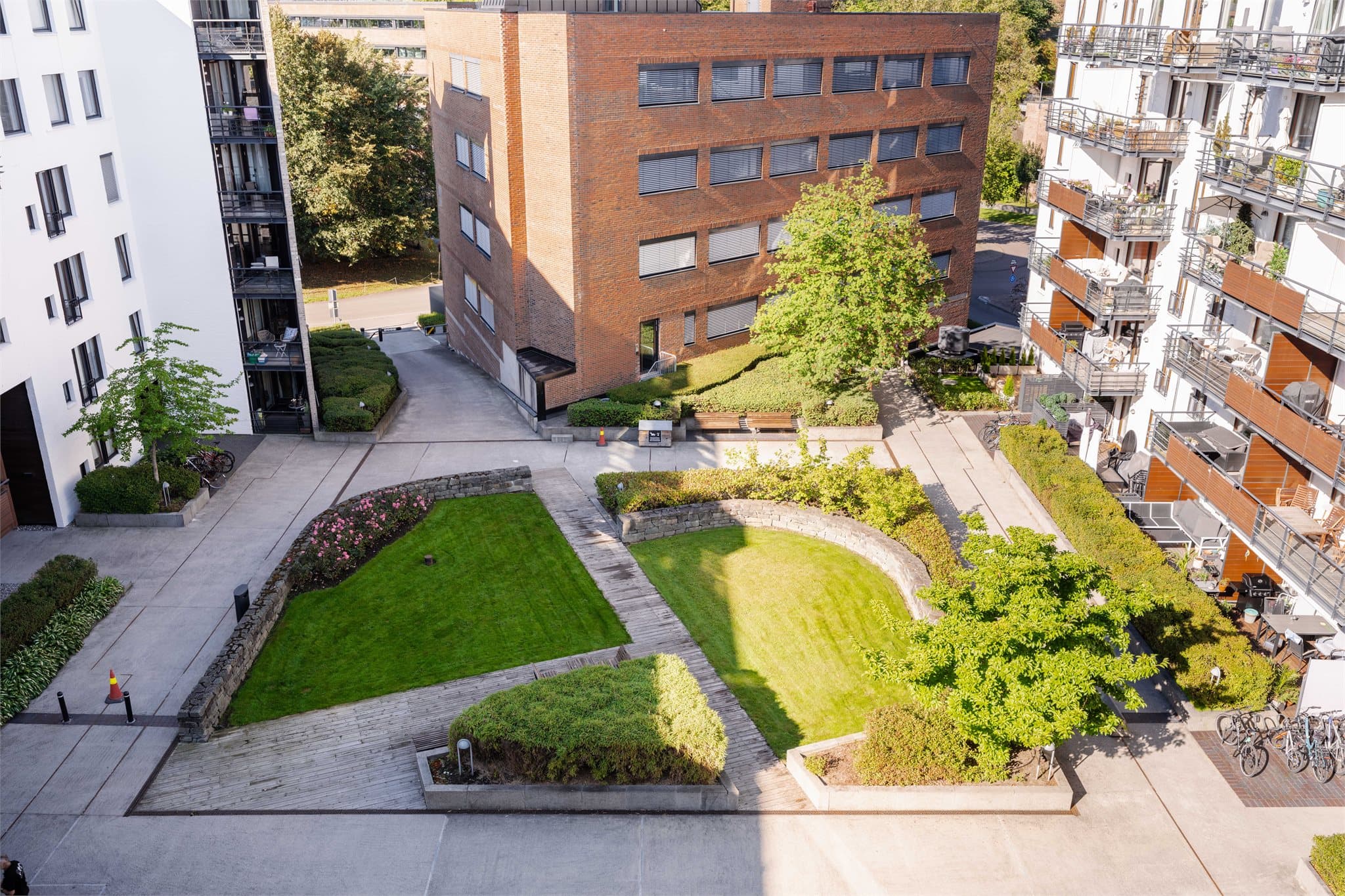 Utsyn over det opparbeidede gårdsrommet med gressplener og beplantning.