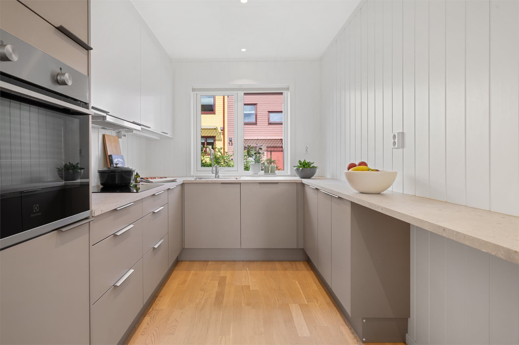 Kjøkkeninnredningen har beige, slette fronter og laminat benkeplate.