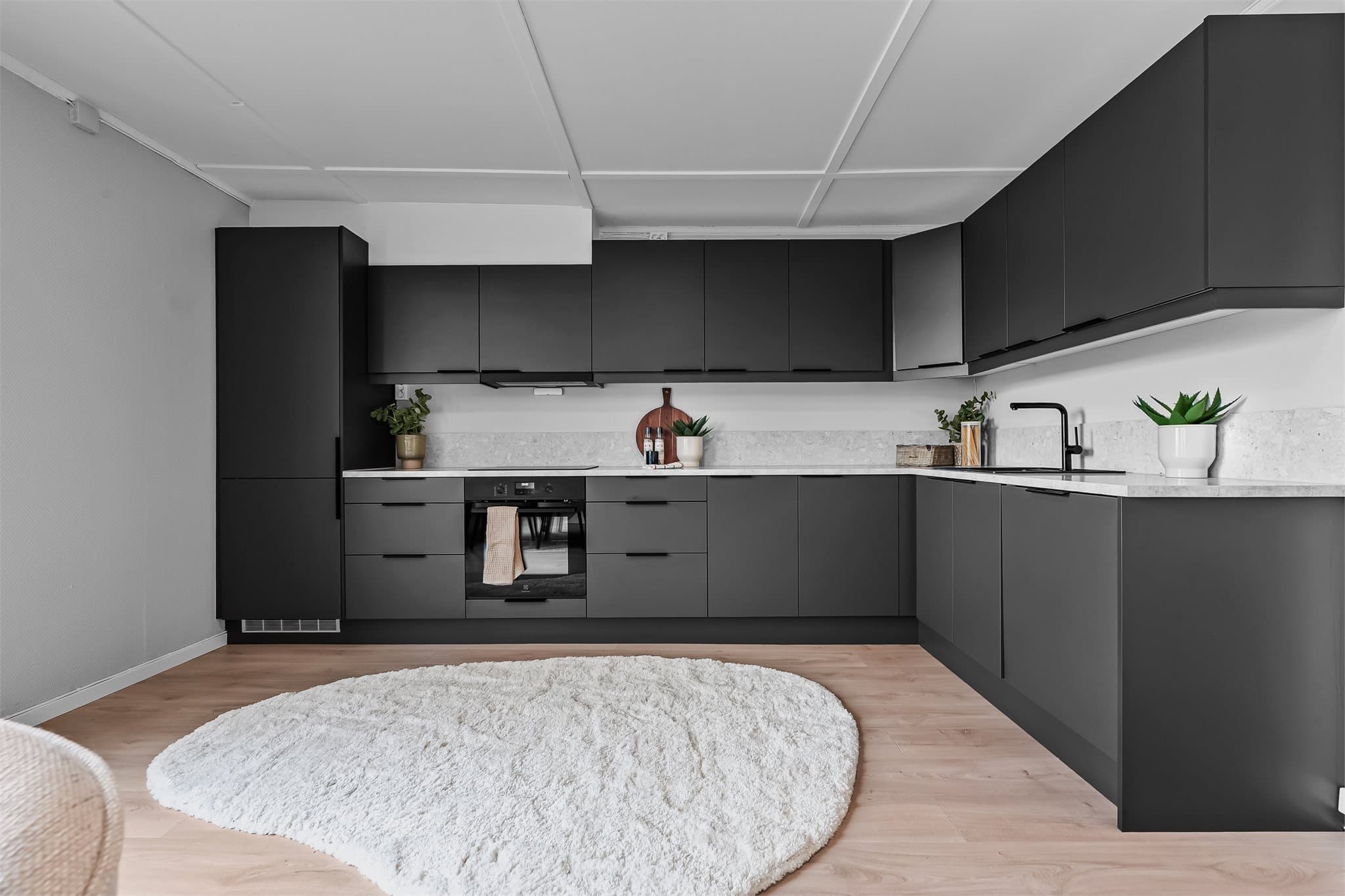 Stilrent kjøkken fra Sigdal med slette fronter og overskap som gir et moderne og tidløst uttrykk. Lys laminatbenkeplate med nedfelt komposittvask og sort ett-greps armatur.