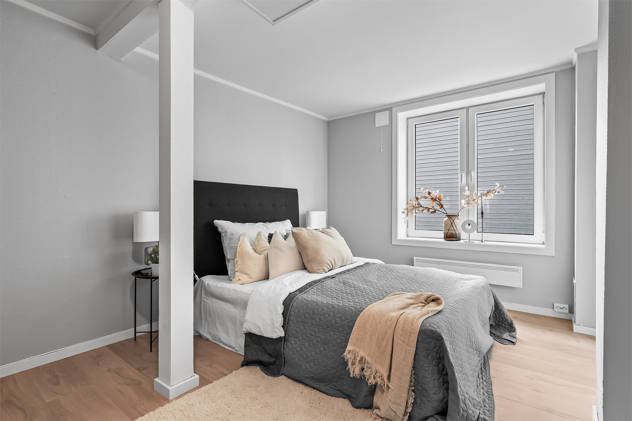 Lyst og romslig hovedsoverom med store vinduer som slipper inn mye naturlig lys