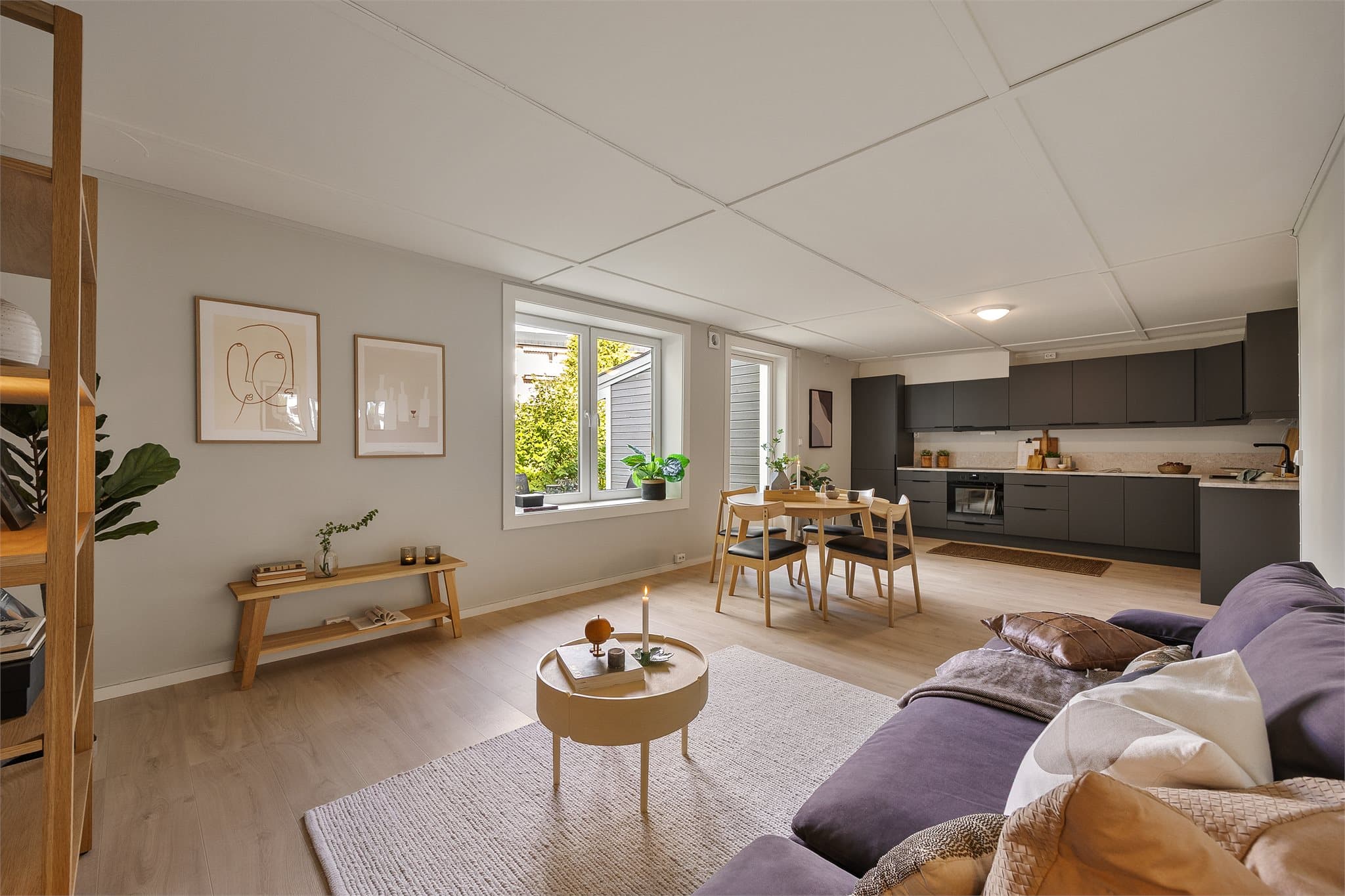 Gjennomgående plan med åpen kjøkkenløsning og spiseplass. Moderne mørke fronter, lys benkeplate og god tilgang til dagslys gjennom store vindusflater.