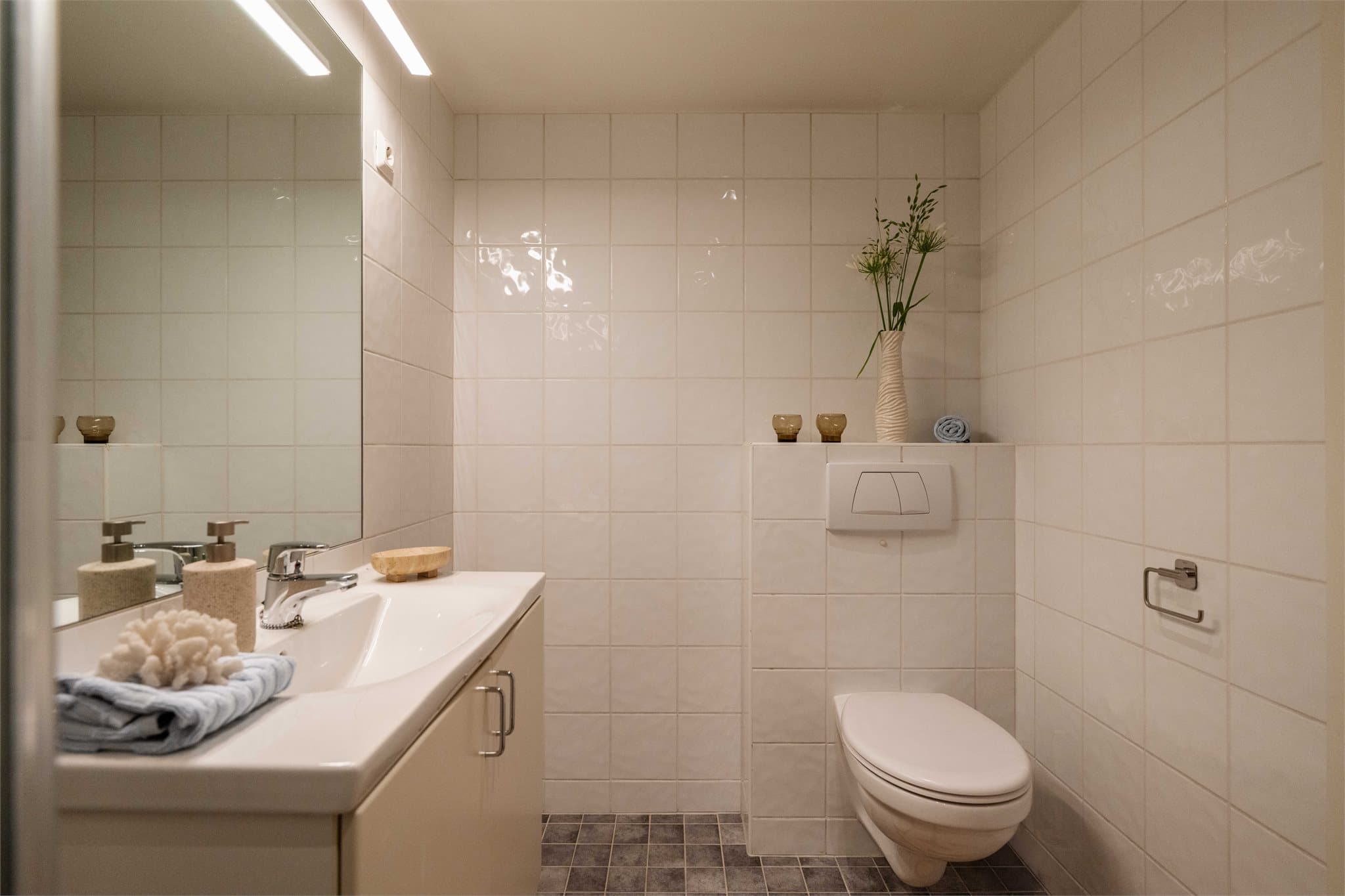 Badet er innredet med vegghengt klosett og servant nedfelt i baderomsinnredning.