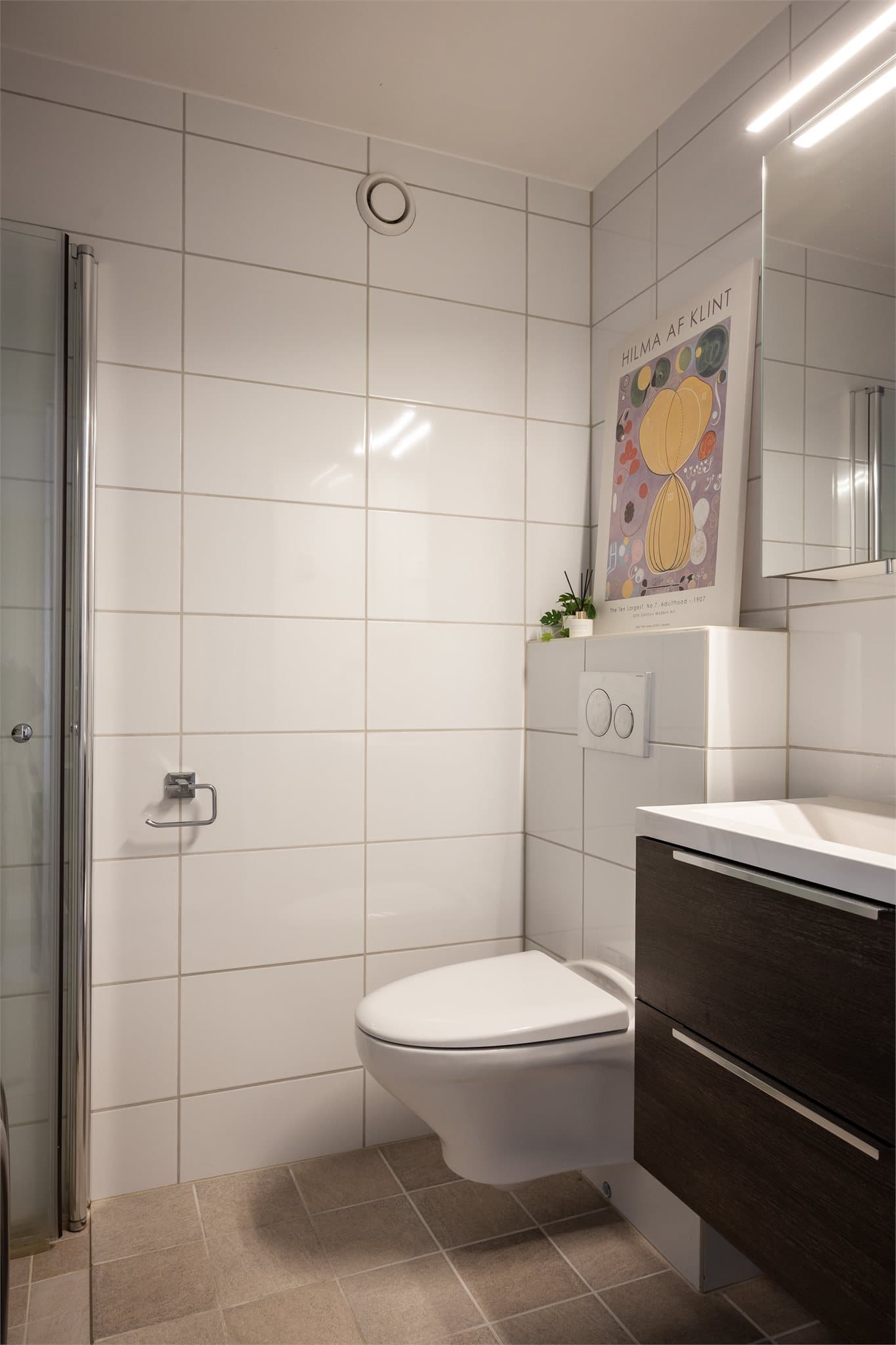 Rommet er utstyrt med et vegghengt toalett med innebygget sisterne.