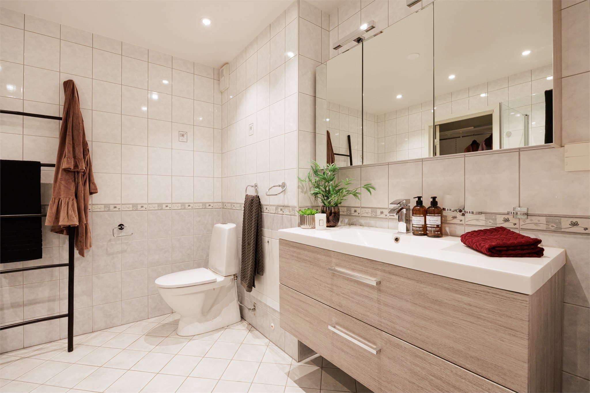 Badet er utstyrt med dusj med innfellbare glassdører, servant, gulvstående toalett og opplegg for vaskemaskin.