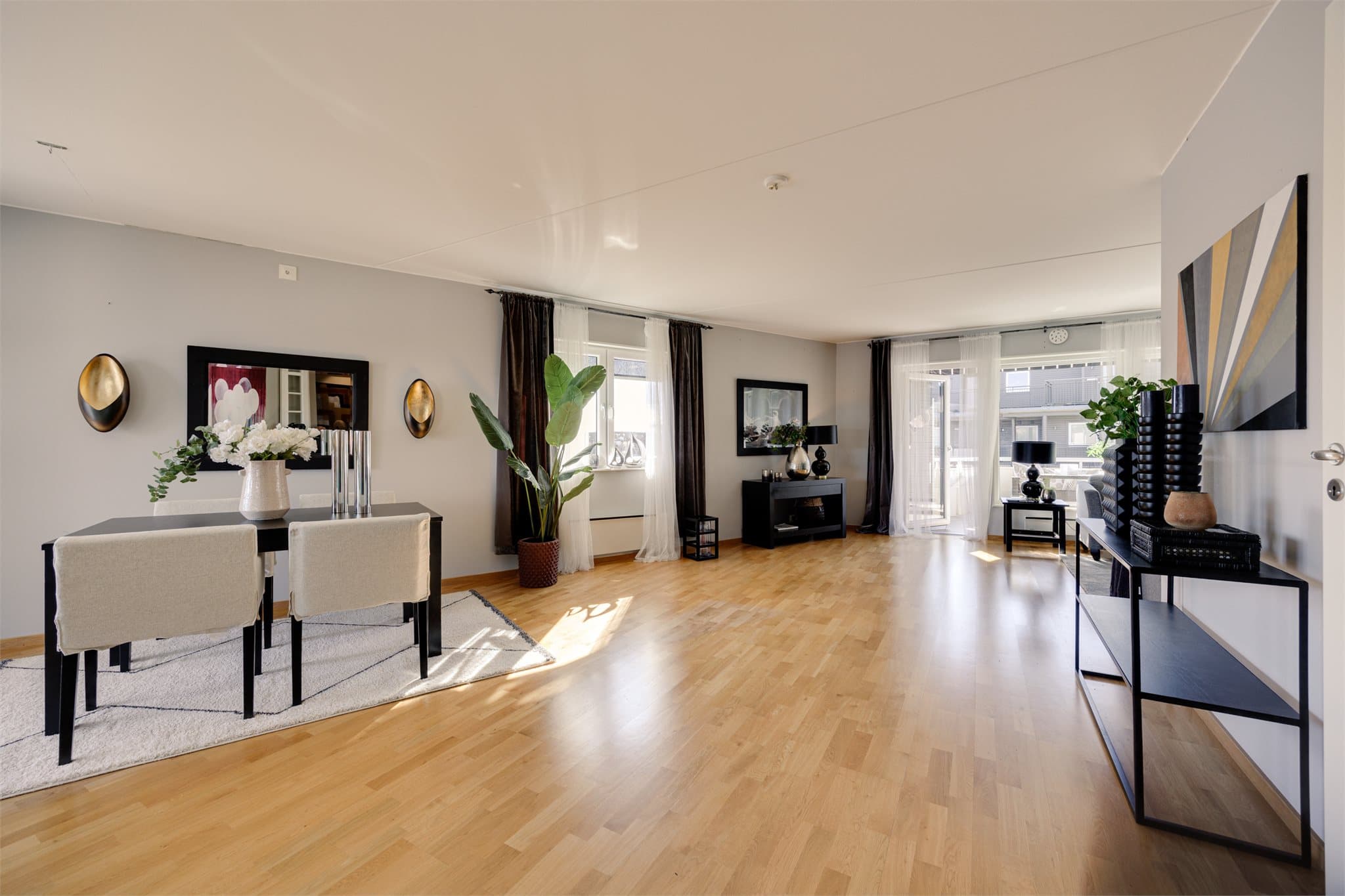 En lys og innbydende stue med store vindusflater som slipper inn rikelig med dagslys fra flere kanter og skaper en luftig og behagelig atmosfære.