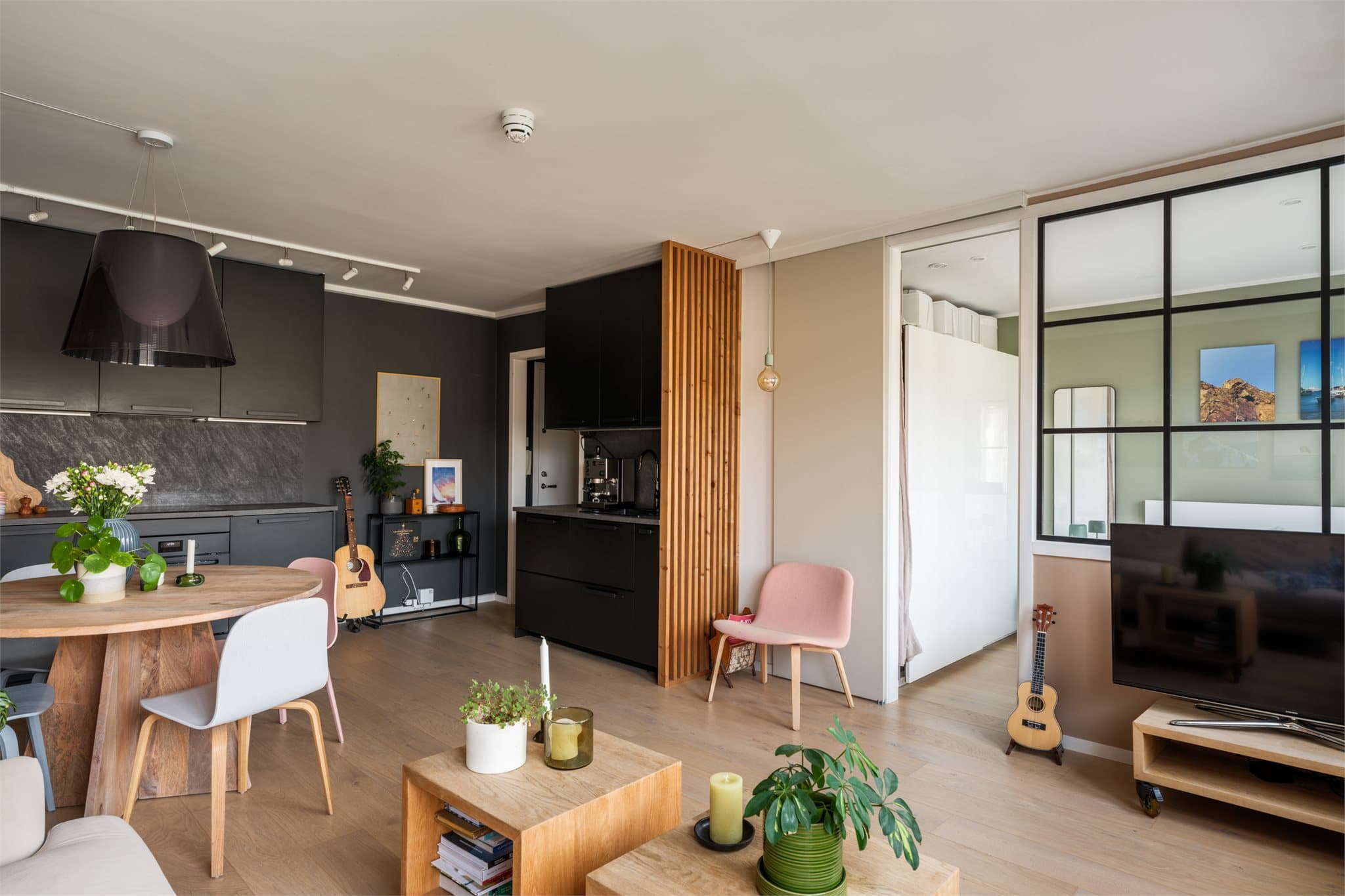 En vegg med skyvedør og glassfelt skiller soverommet fra stuen på en elegant måte.