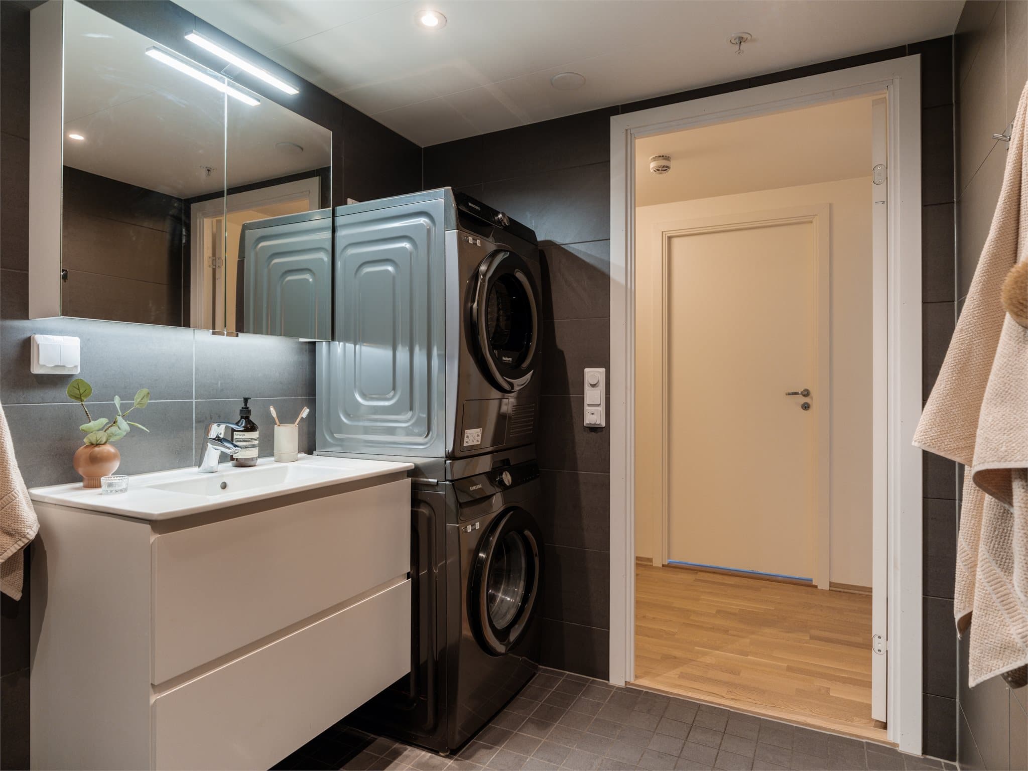 Servantskap med heldekkende servant, speilskap med lys og opplegg for både vaskemaskin og tørketrommel.