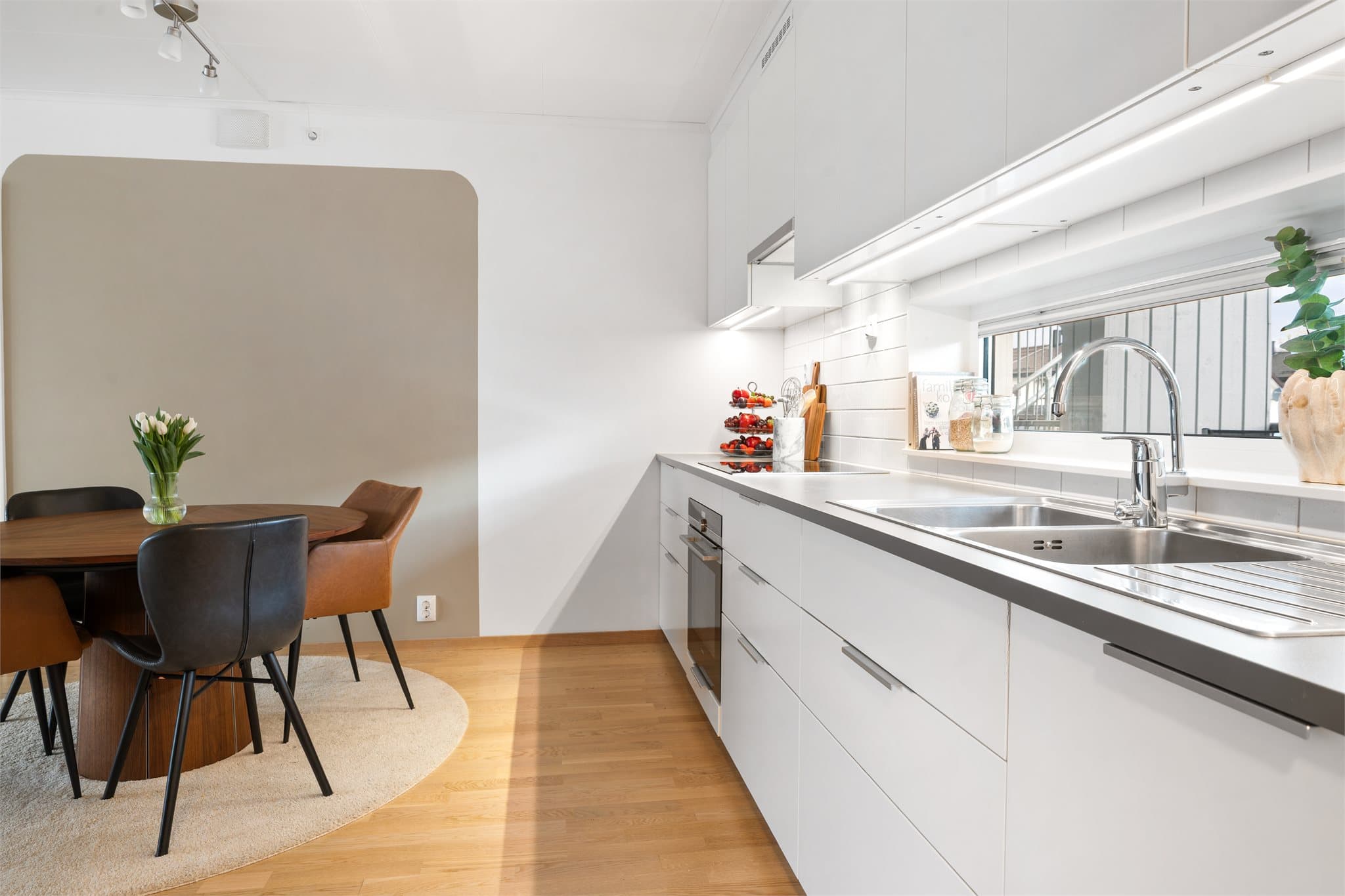 Kjøkkeninnredningen har hvite, slette fronter og laminat benkeplate.