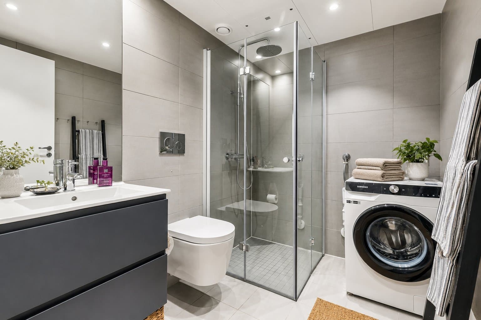 Leiligheten har et delikat bad, med et moderne preg. Innredningen har glatte fronter, servant over servantskap, dusjhjørne med svingbare glassvegger, vegghengt toalett og det er opplegg for vaskemaskin. Badet har vannbåren gulvvarme.