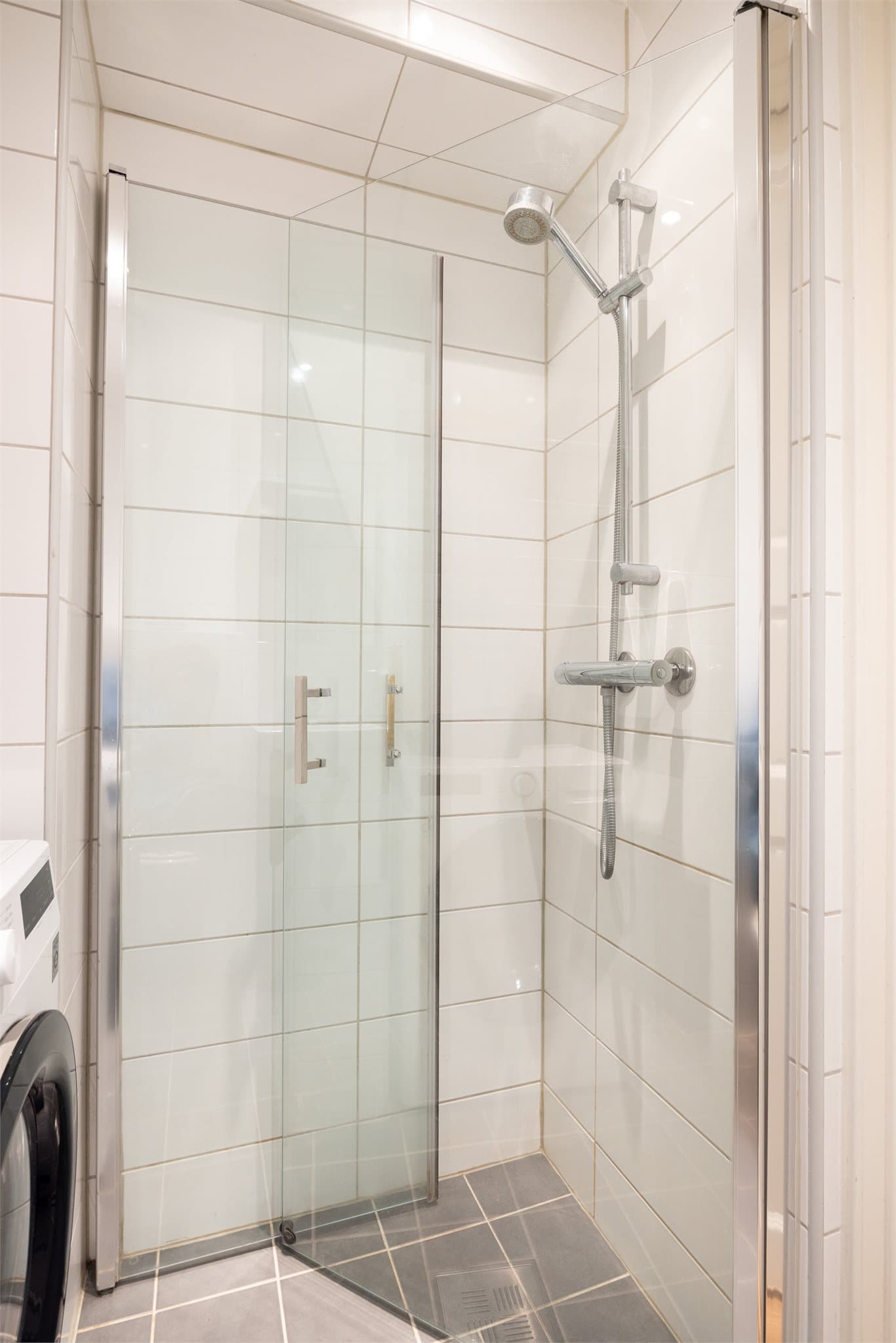 Inneholder blant annet grå 20x20 fliser på gulv, hvite 20x50 fliser på vegger og gips-himling med downlight.