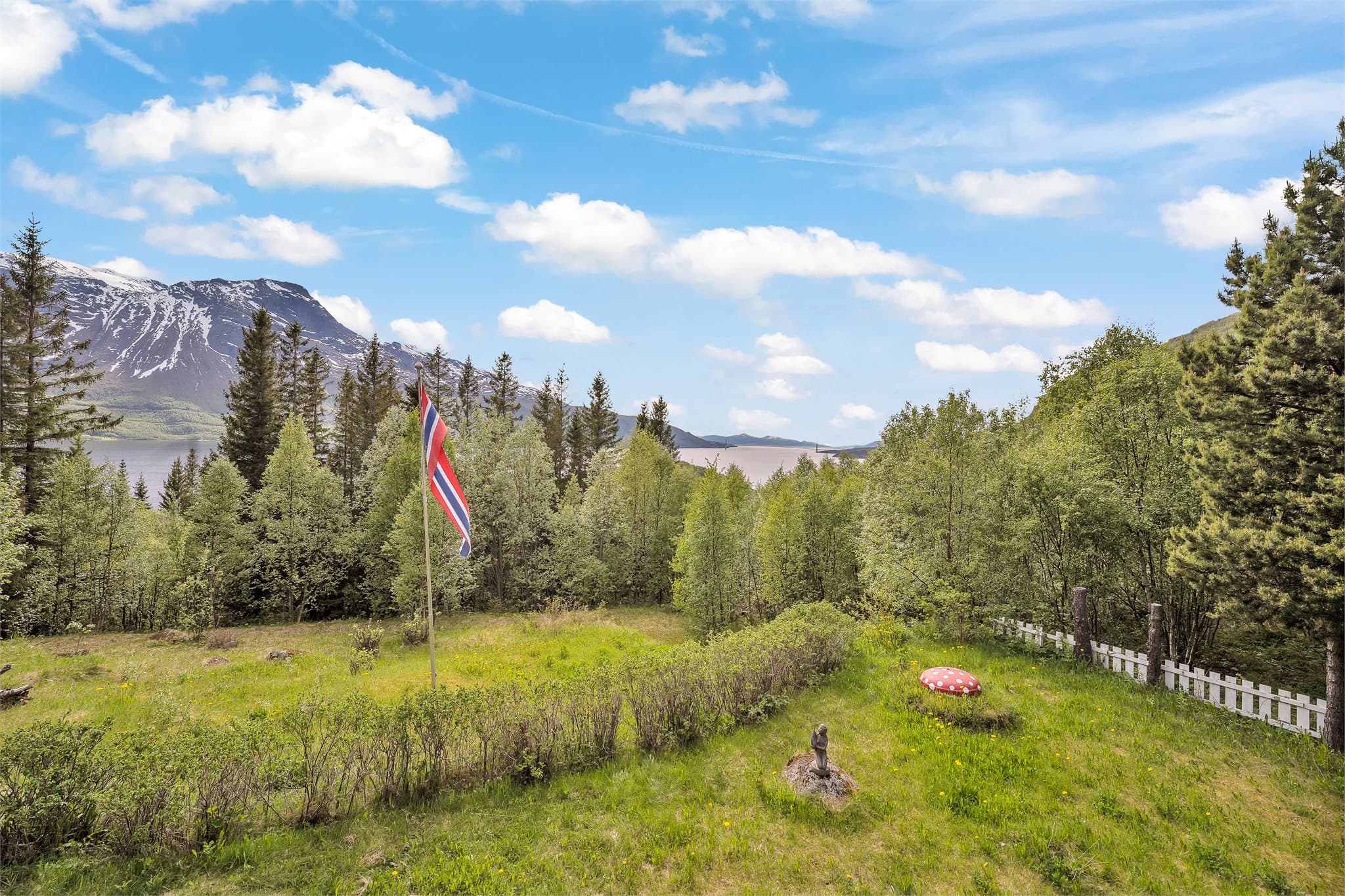 Utsikt fra terrassen mot hagen, fjorden og fjellene
