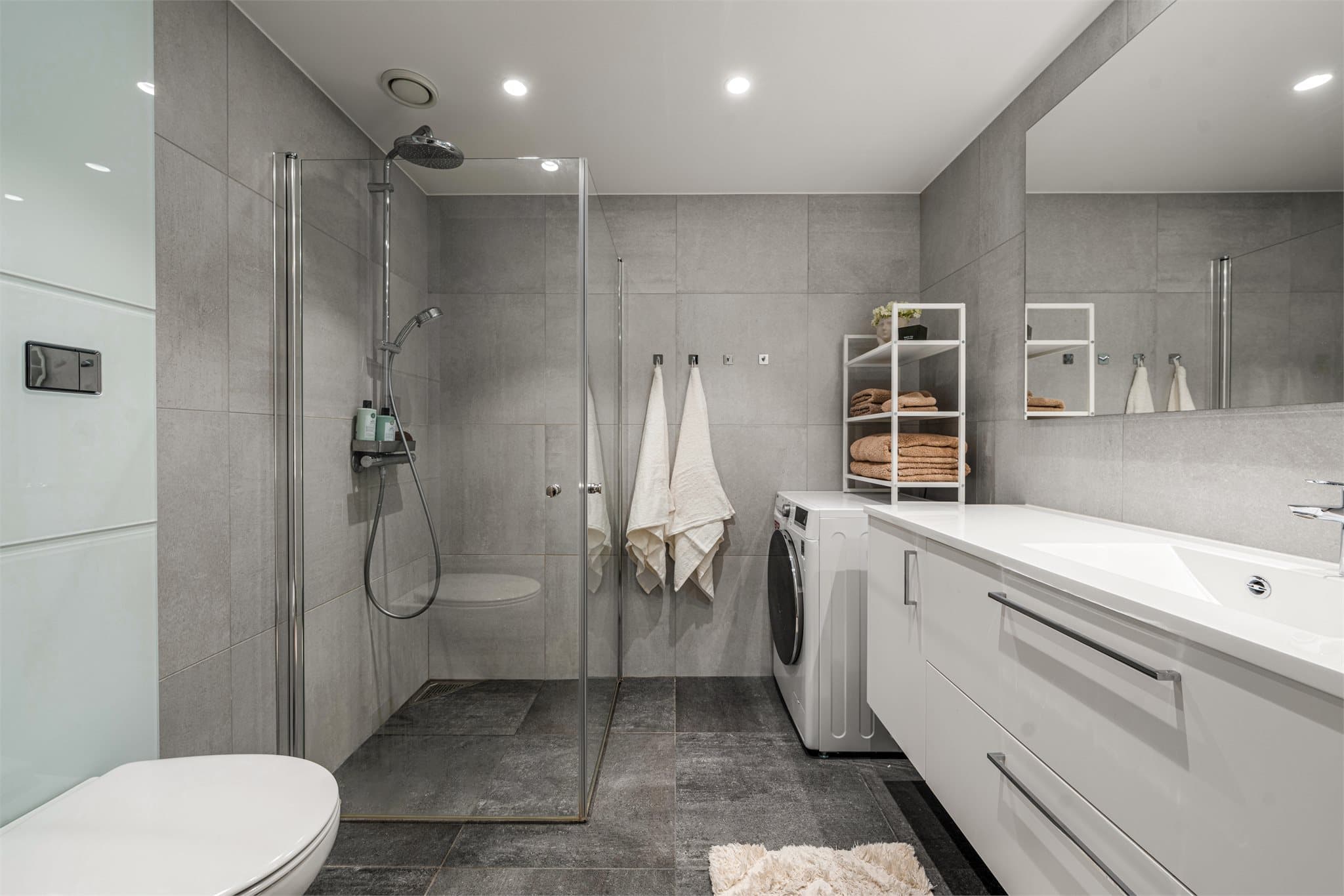 Lekkert baderom med moderne flisvalg, elektriske varmekabler og spotter i tak.