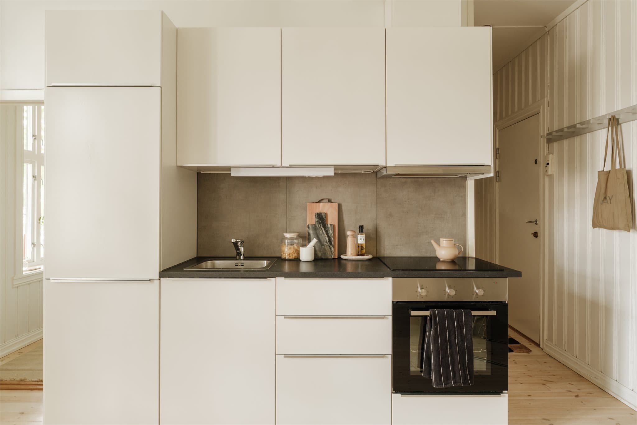 Et lyst og delikat kjøkken med integrerte hvitevarer som stekeovn, platetopp og oppvaskmaskin.