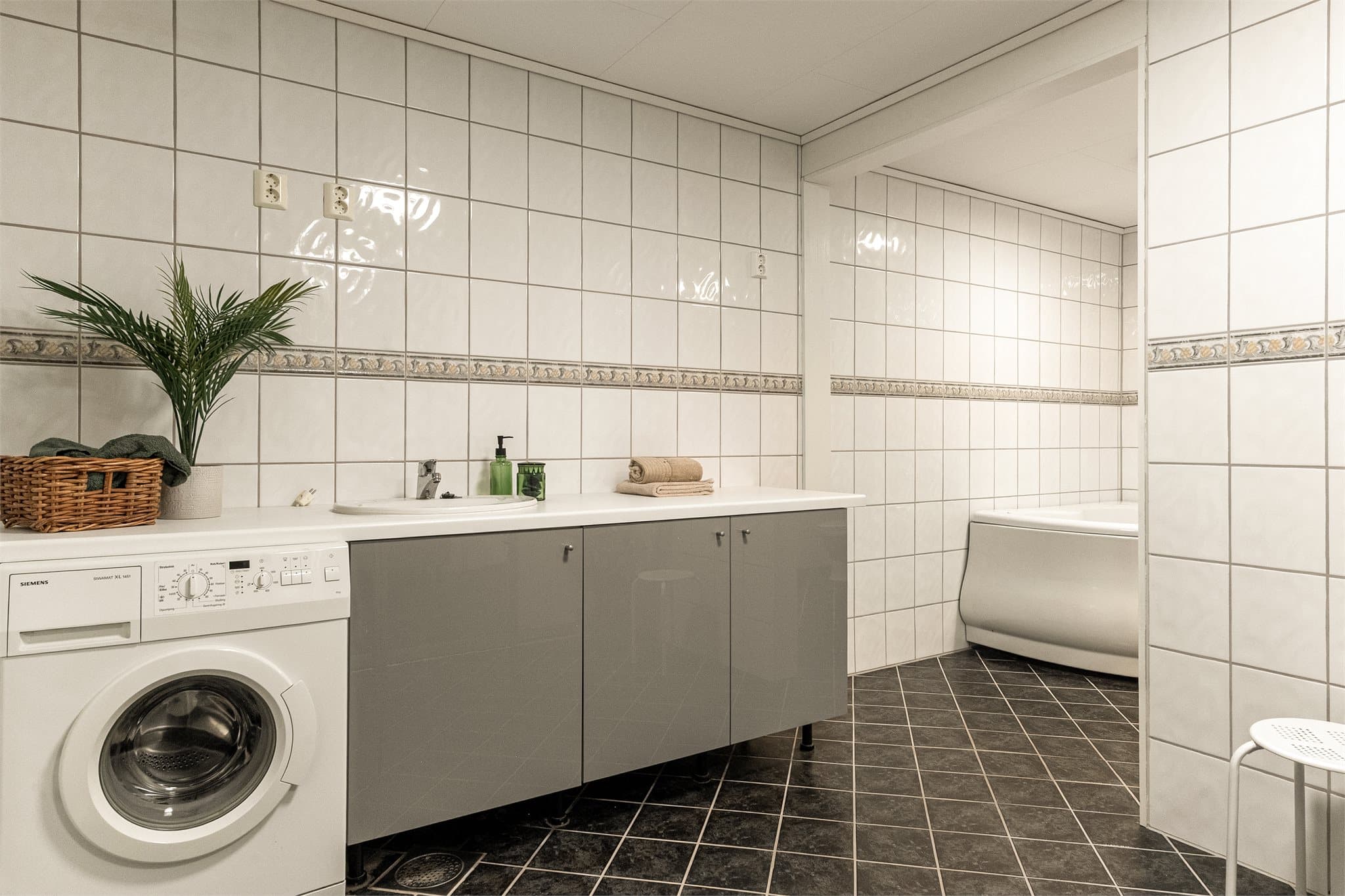 - Rommet inneholder badekar, toalett, servant med underskap, opplegg for vaskemaskin og benkeskap med laminat og vask -