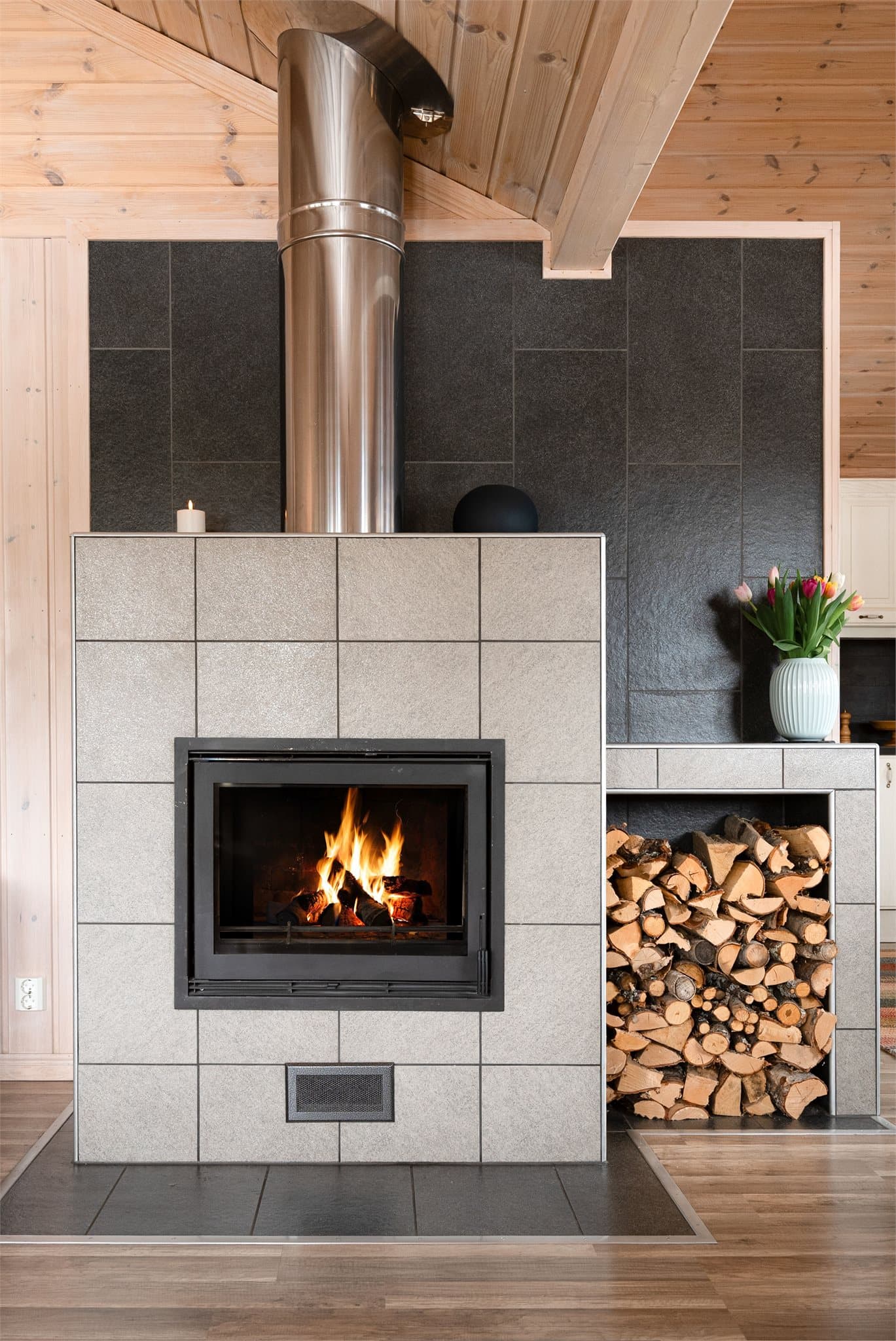 Peisovnen har et pent og funksjonelt design, med plass til oppbevaring av ved og mulighet for enkel dekorasjon.