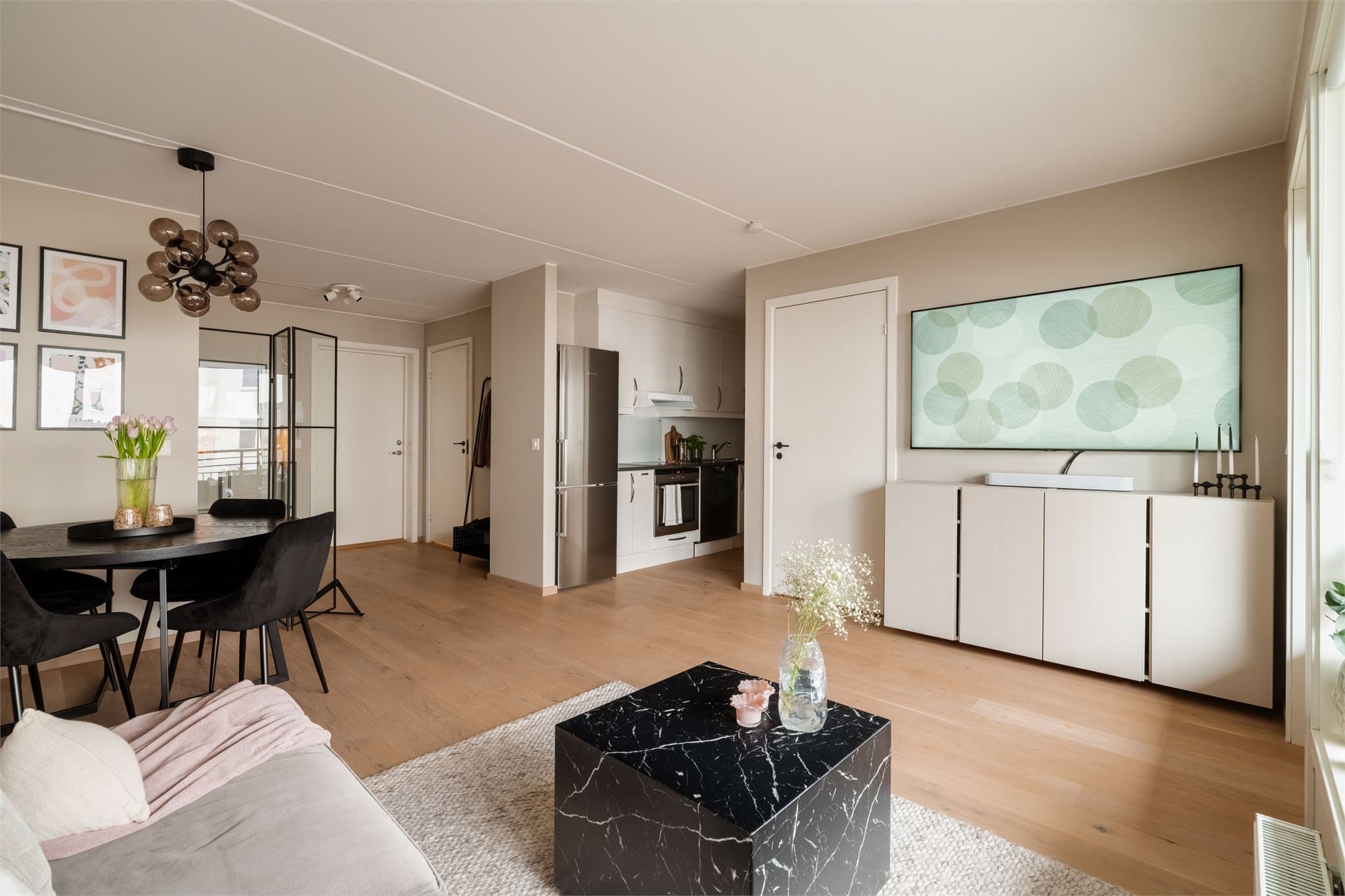 En åpen og sosial sone som binder sammen stue, spiseplass og kjøkken.