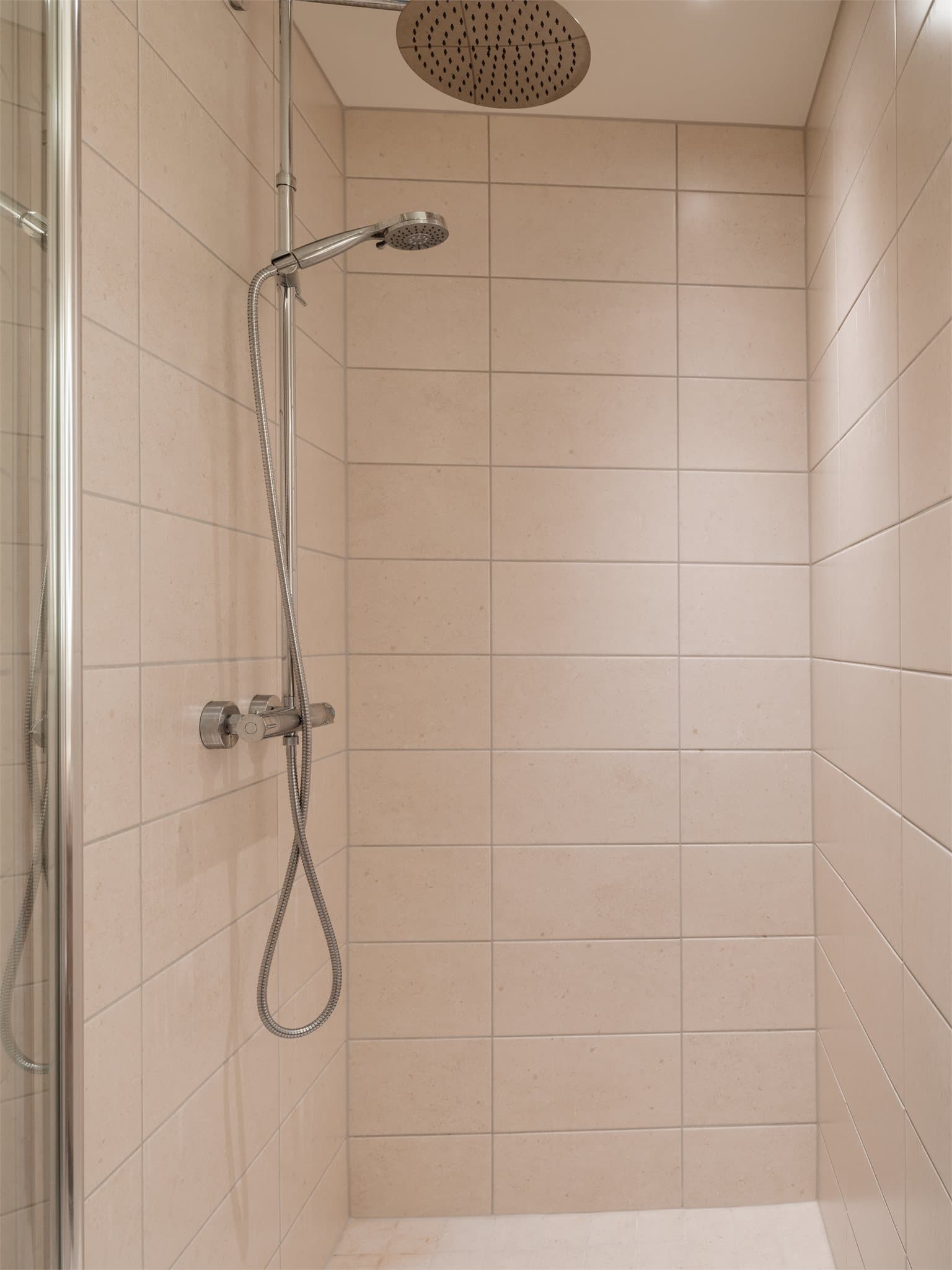 Regnfallsdusj og glassdører i dusjsonen.