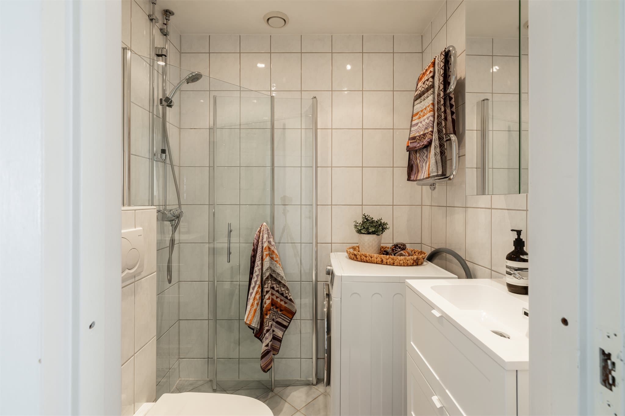 Badet har flislagte gulv, flislagte vegger, malte plater i tak og varmekabler i gulv.