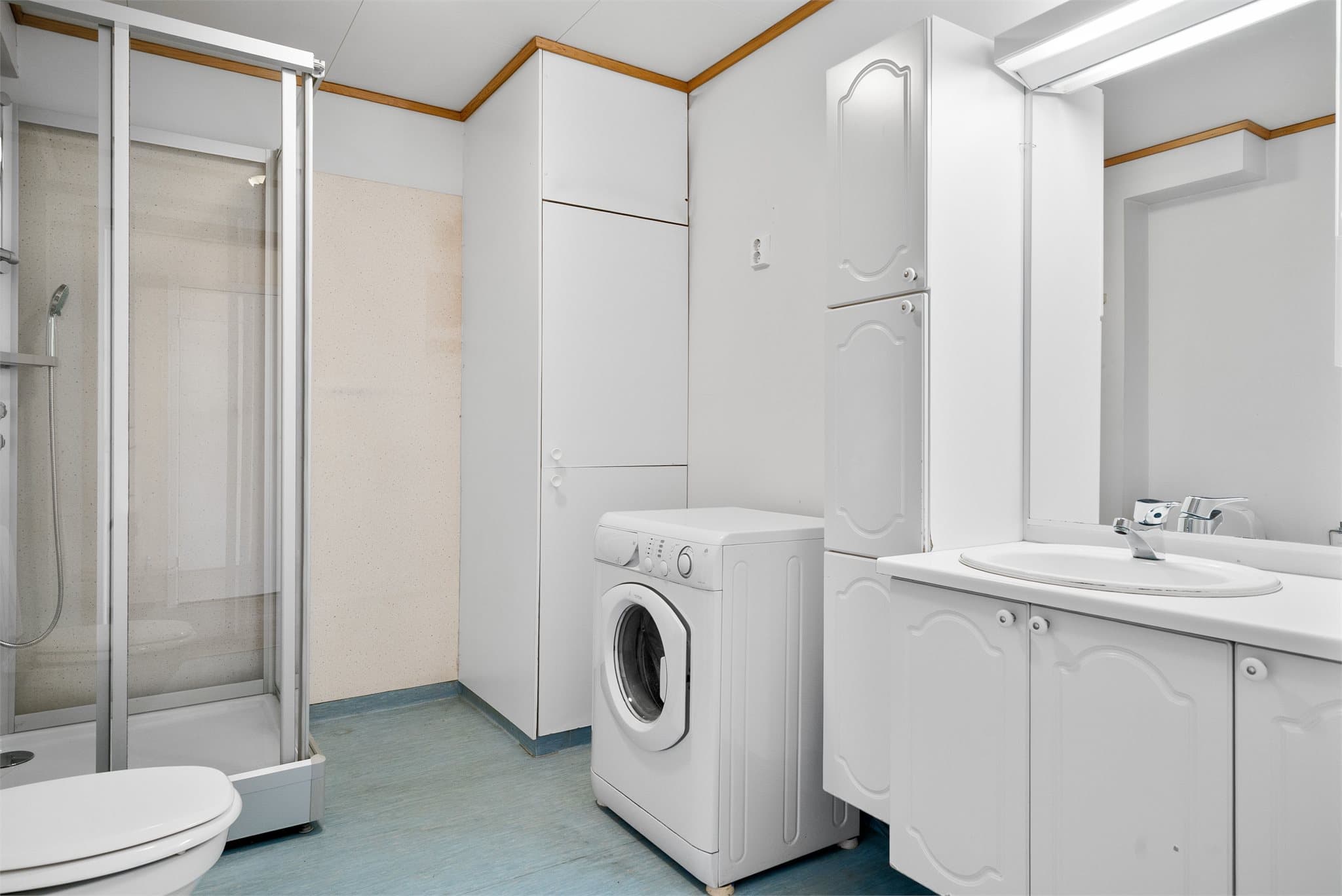 Badet måler 7 kvm og er utstyrt med servantinnredning, skap, dusjkabinett, toalett og opplegg for vaskemaskin.