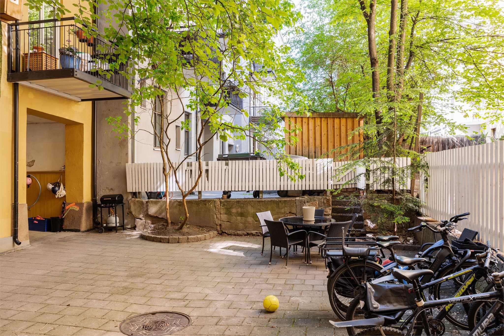Felles bakgård med steinbelagt uteplass og sykkelparkering.