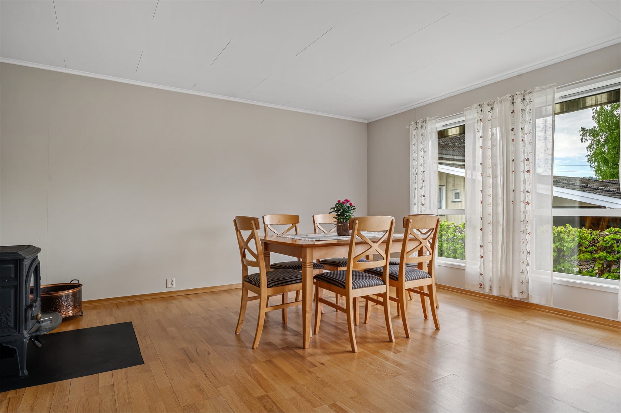 Den romslige spisestuedelen har god plass til større spisebord ved vinduene, hvor man kan nyte utsyn mot hagen og et flott lysinnslipp.