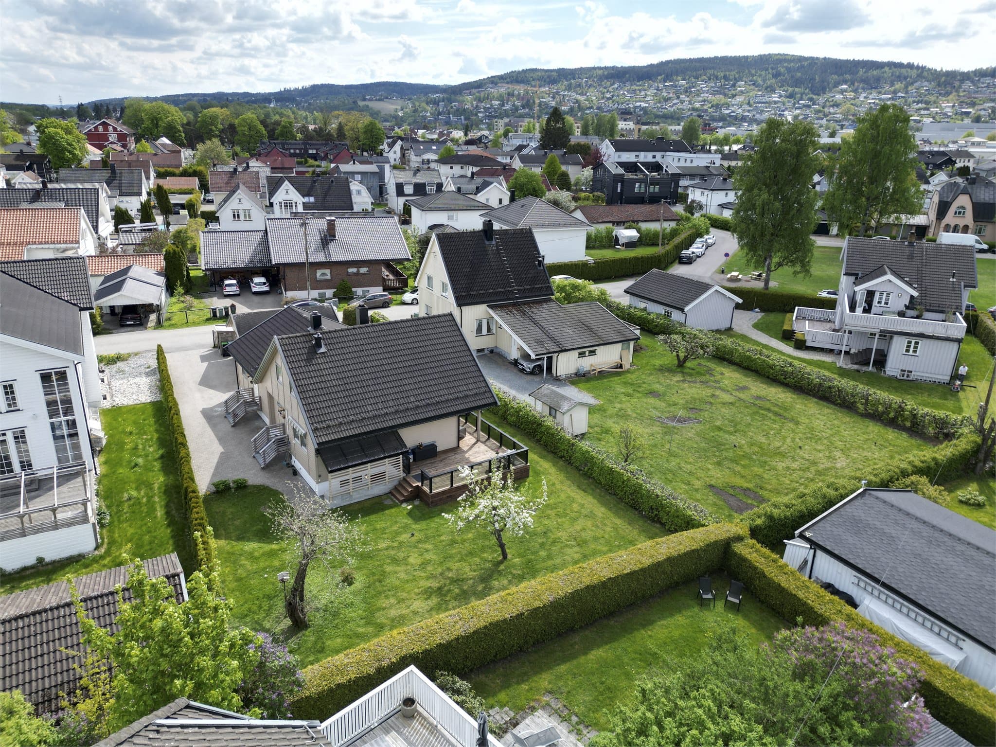 Dronebildene gir et helhetlig inntrykk av den innholdsrike generasjonsboligen med to boenheter og flotte utearealer i etablerte omgivelser.