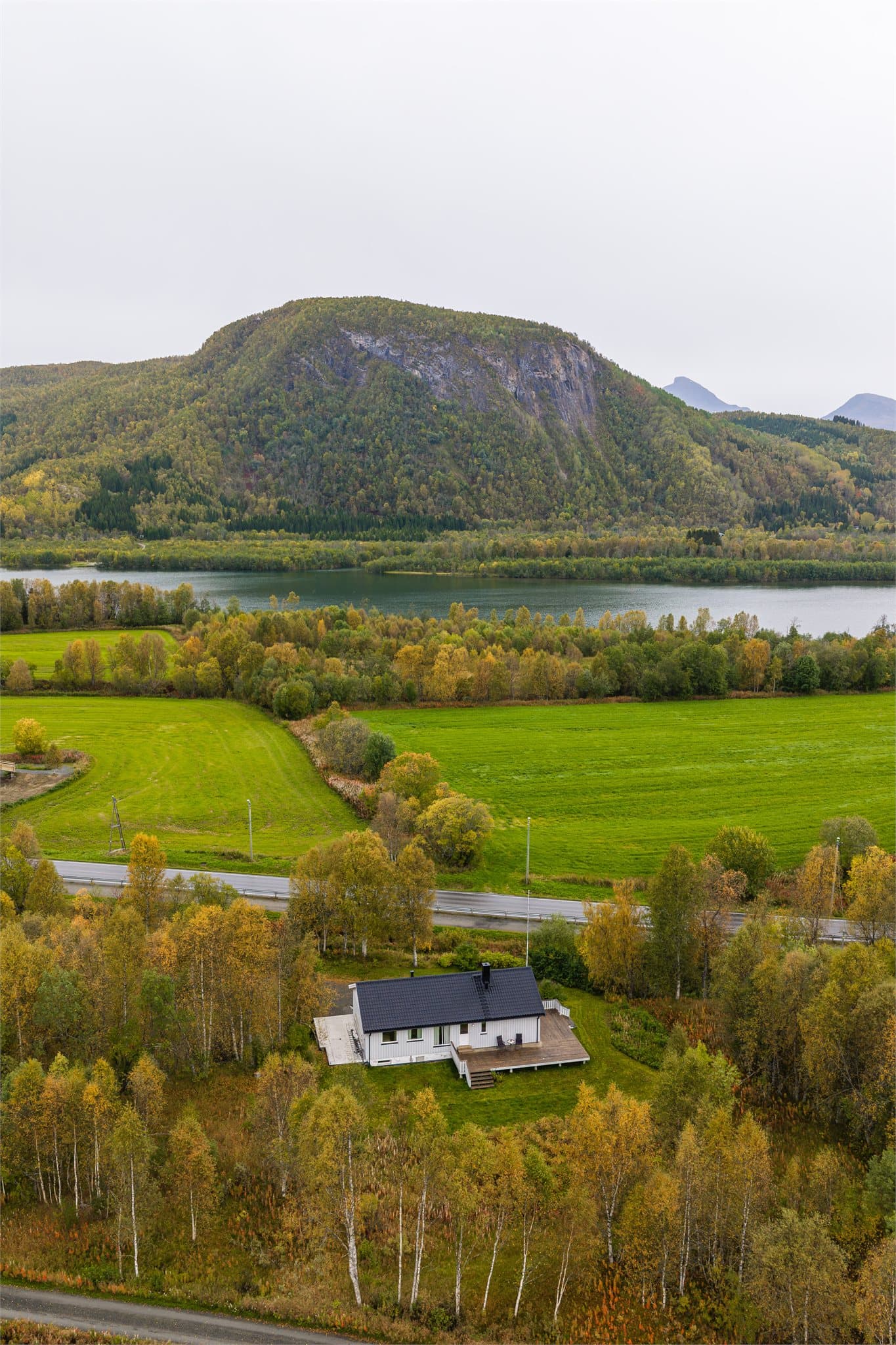 Frodig tomt omkranset av skog og åpne åkerlandskap langs elva.